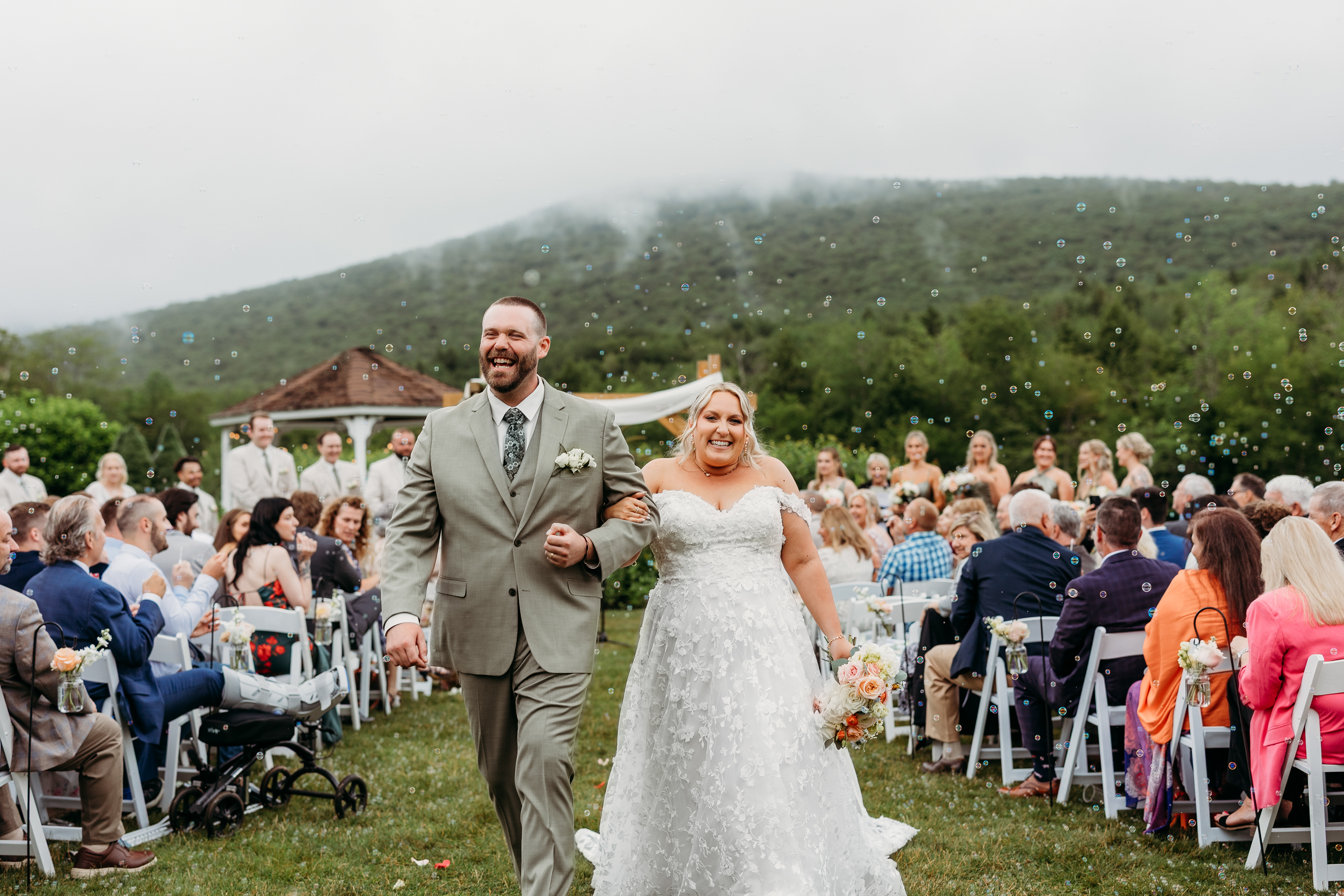 Guests tossing bubbles, sunlight breaking through — a dreamy New England wedding celebration.