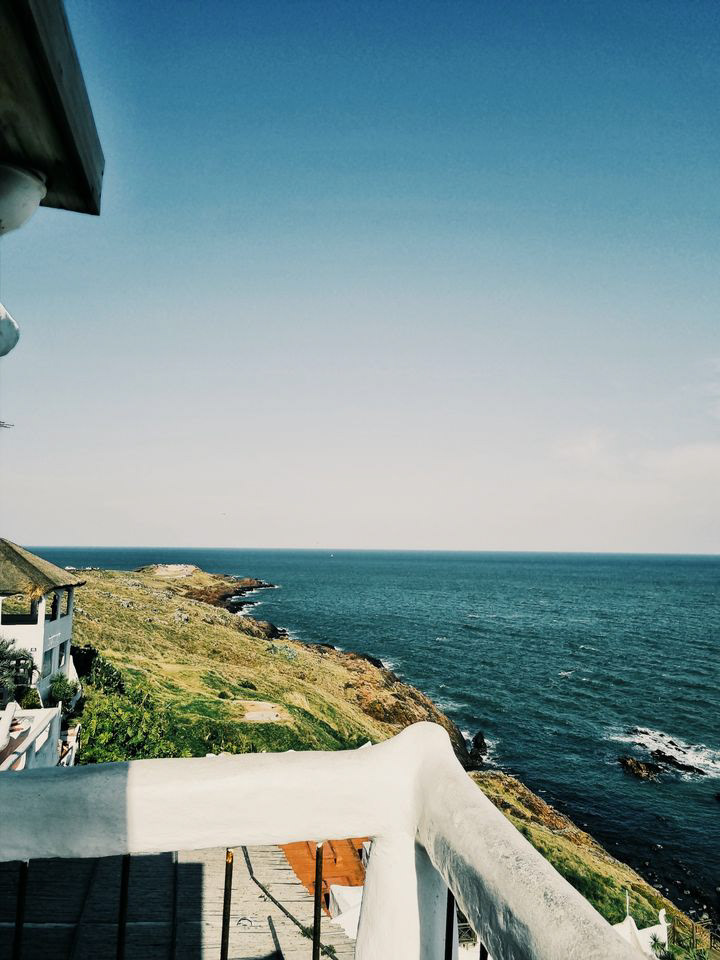 The gentle curves of a seaside balcony offer a serene vantage point over the endless blue of the ocean, where sky and sea meet in perfect harmony