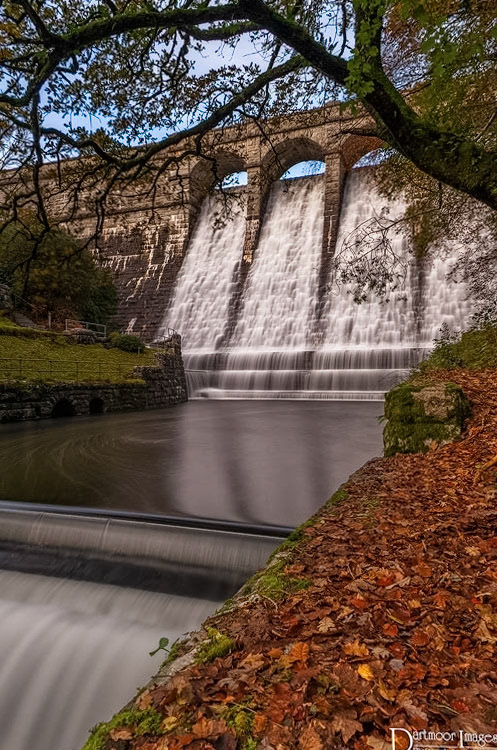 Water from the Burrator Reservoir on Dartmoor National Park falls over the dam and into the River Meavy during an autumn afternoon.