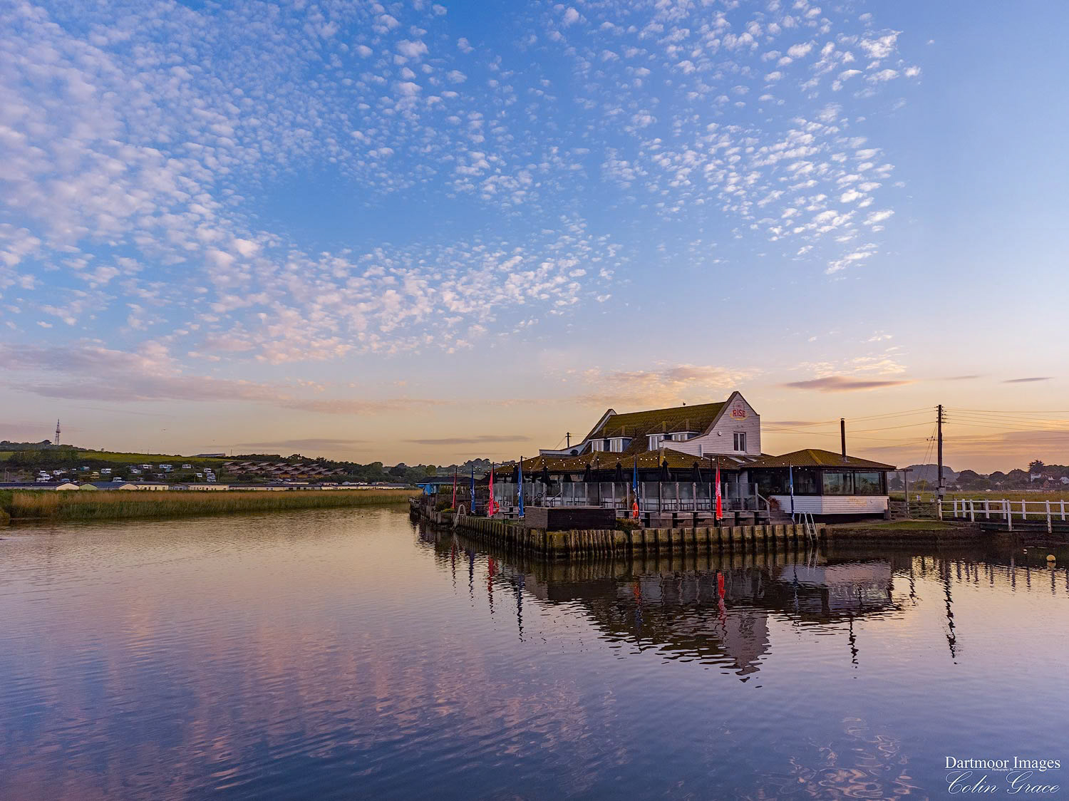Rise cafe and bar in West Bayiis reflected in still waters as the begins to rise over Dorset.