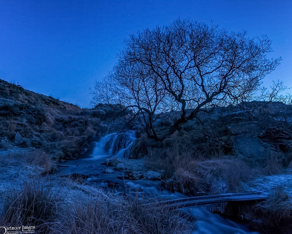 An hour before sunrise and the last of the nights stars are just visible as the River Meavy gently tumbles over Black Tor Falls on Dartmoor. It was a very cold night as what light is available reveals a heavy ground frost and icicles hanginging below the improvised bridge that spans the river.