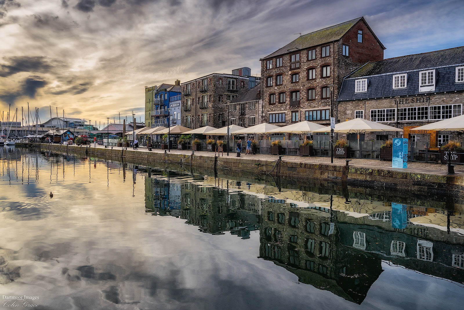 Still waters reflect the clouds and buildings of the Barbican in the old park of Plymouth.