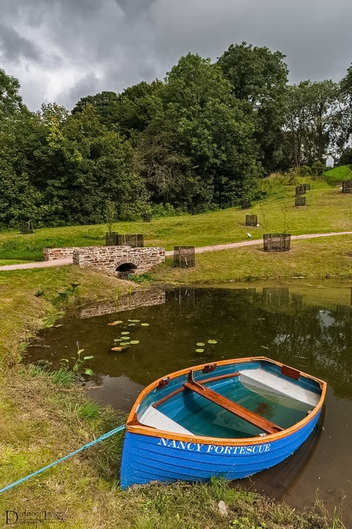 A small boat named Nancy Fortescue tied up alongside the small lake in the new arboretum in The Garden House just outside Plymouth in Devon.