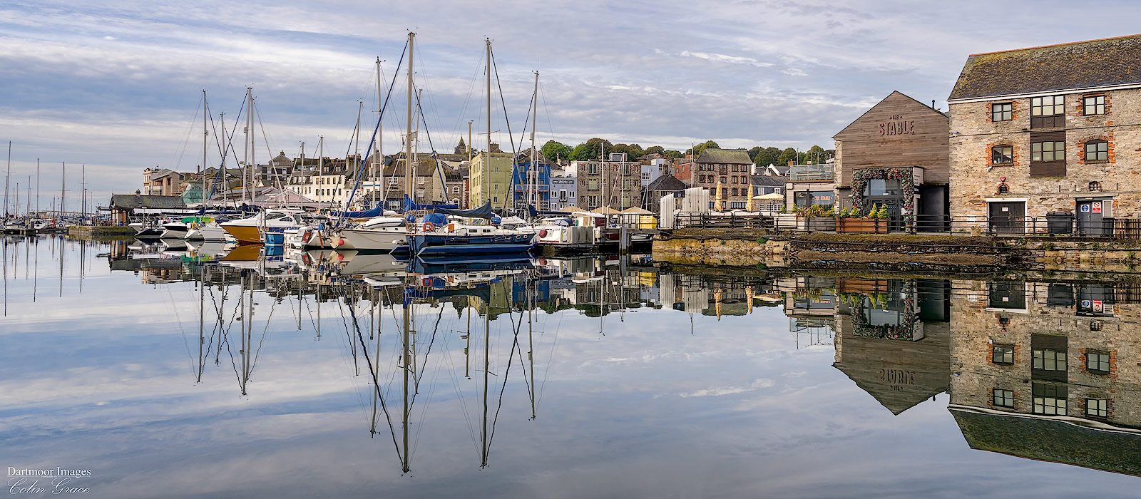 Boats and buildings reflected in the still waters of  Sutton Hsrbour in Plymouth.