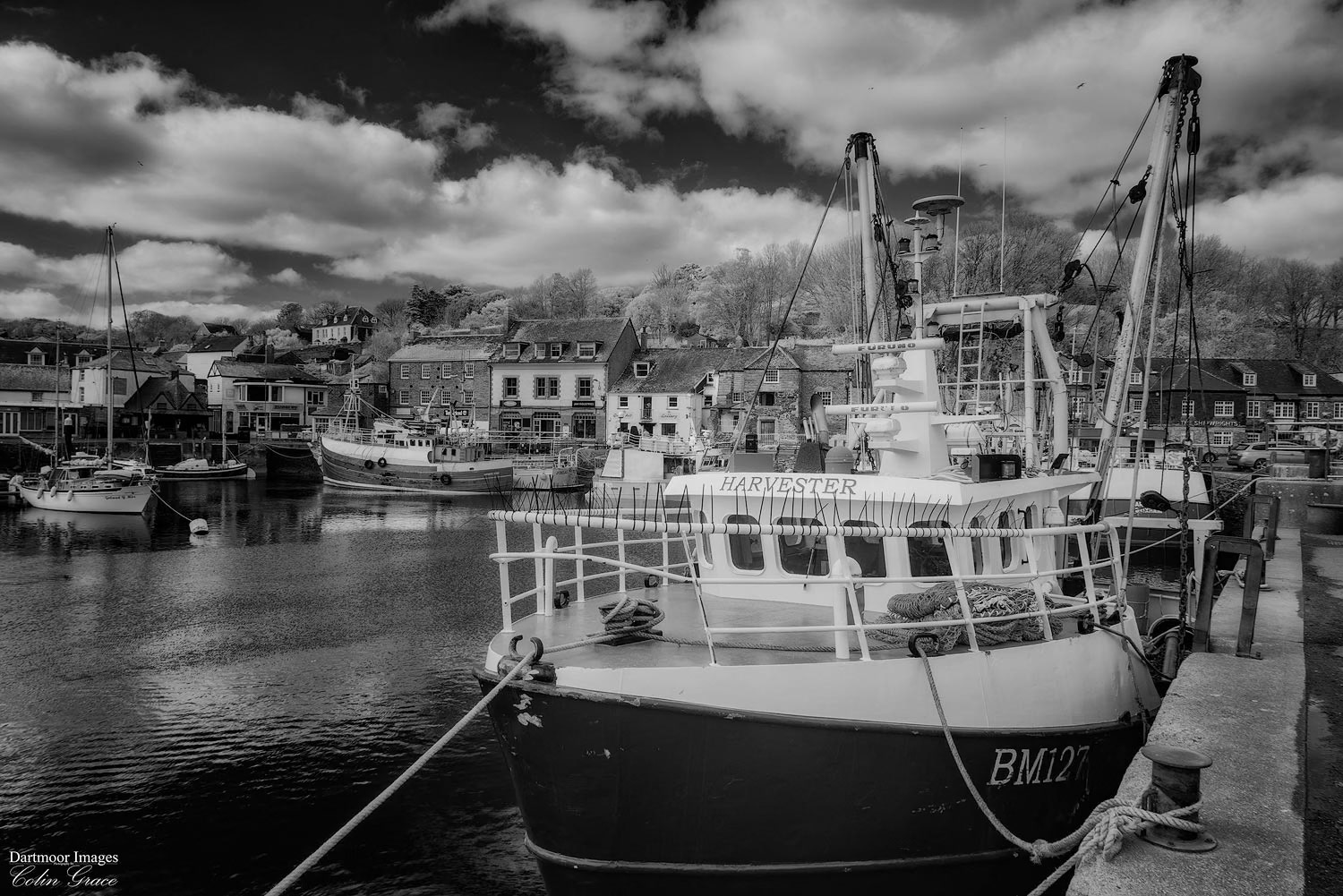 The fishing vessel Harvester tied up alongside the harbour at Padstow during a cloudy but warm spring day in Cornwall.