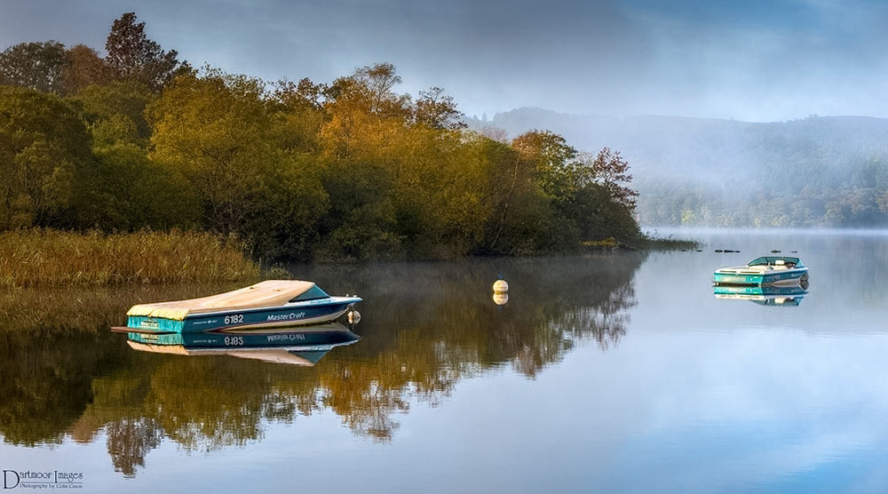 An early morning mist hangs over the still waters of Windermere on Lake District National Park.