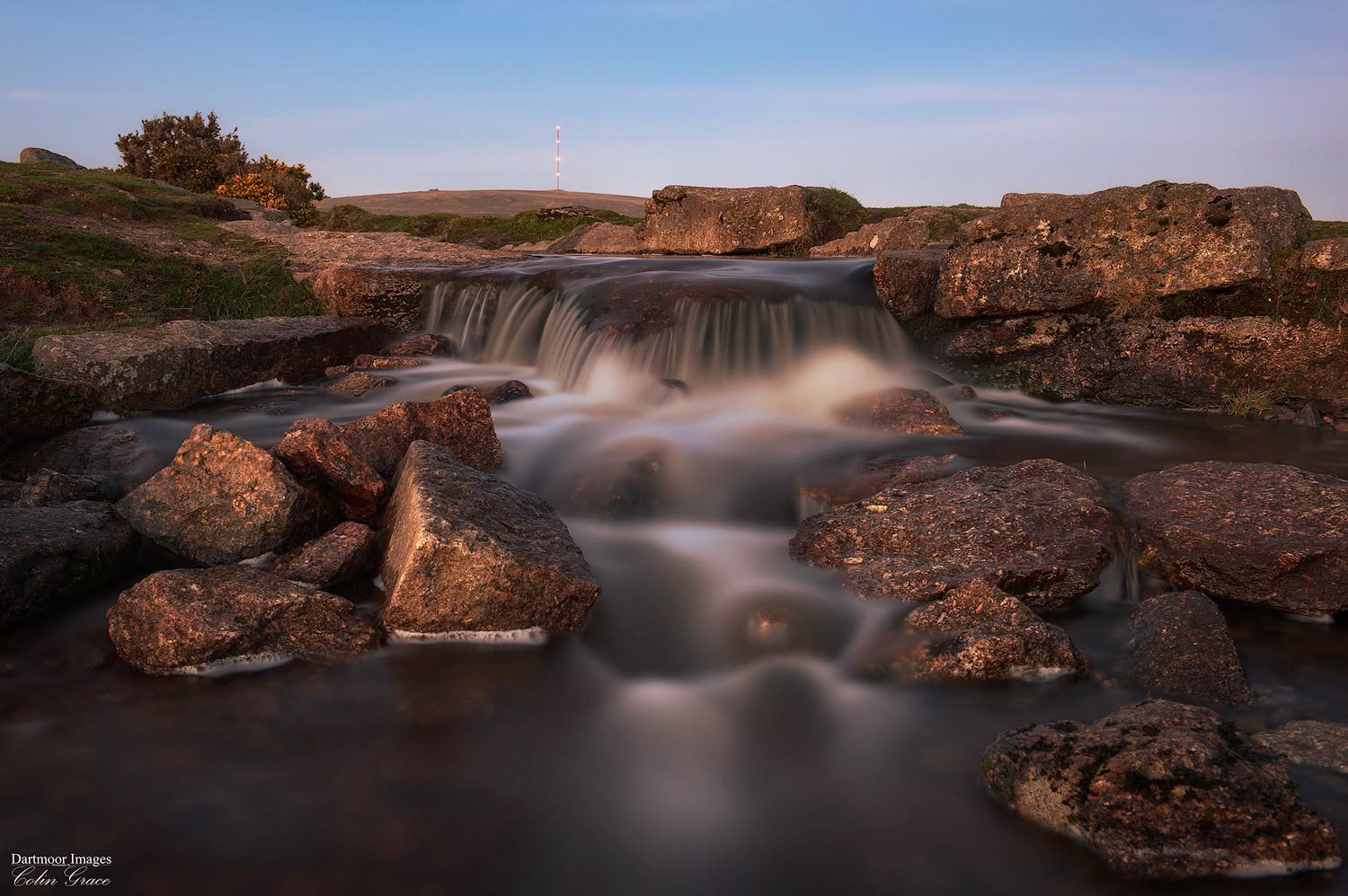Water of the Grimstone and Sortridge Leat flows over the rocks at Windy Post during dusk on Dartmoor.