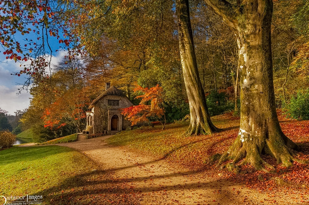 An early autumn morning at Stourhead Gardens in Wiltshire. As the sun rises above the trees on the opposite side of the lake, it casts a shadow over the Gothic Cottage and surrounding trees.  At the same time it highlights the fabulous colours that the gardens have to offer at this time of the year and season.