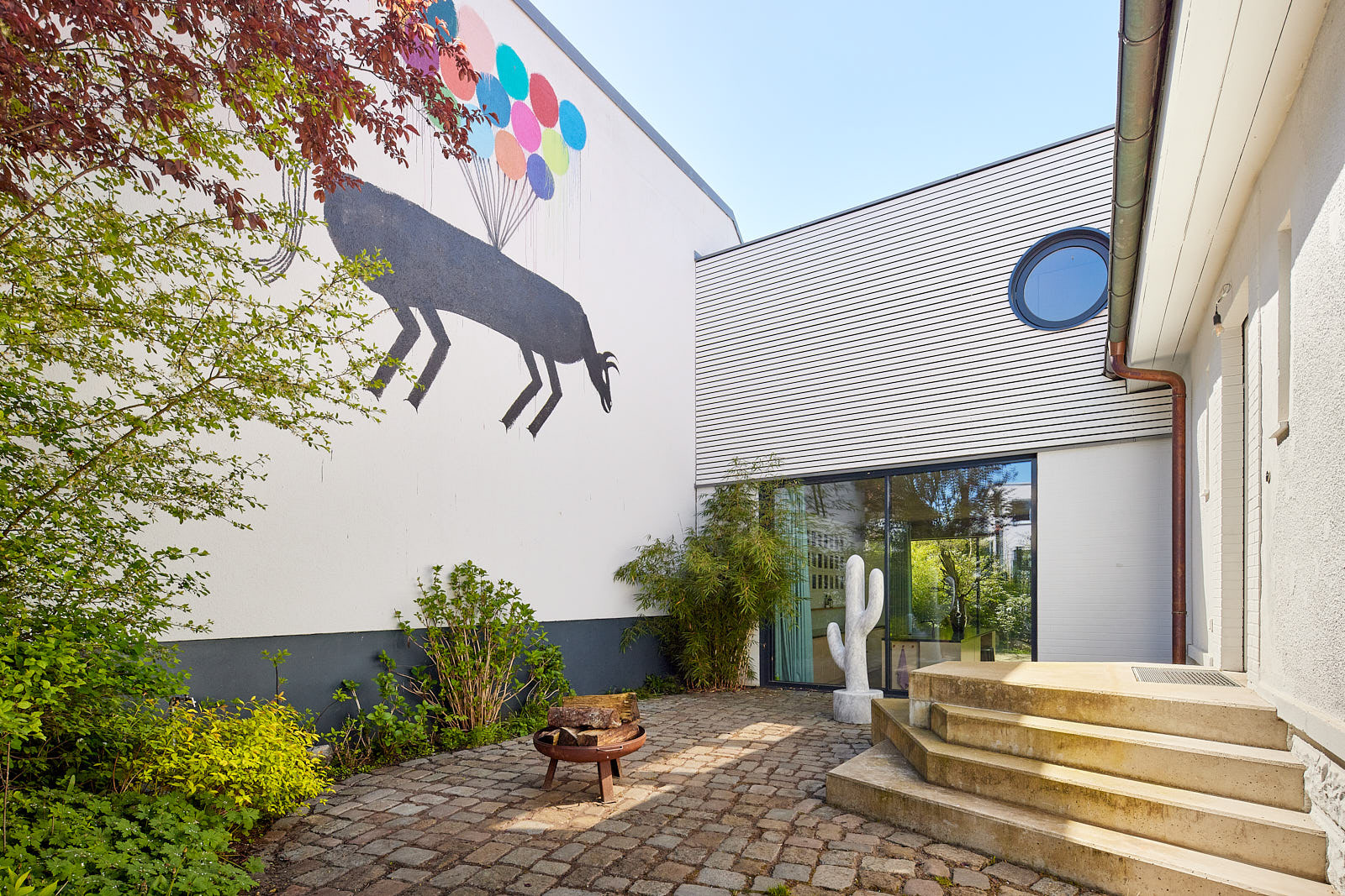 Eingangshof der Villa Bloomgarden mit Kunst an der Fassade und Übergang zwischen historischem Wohnhaus und Erweiterungsbau.