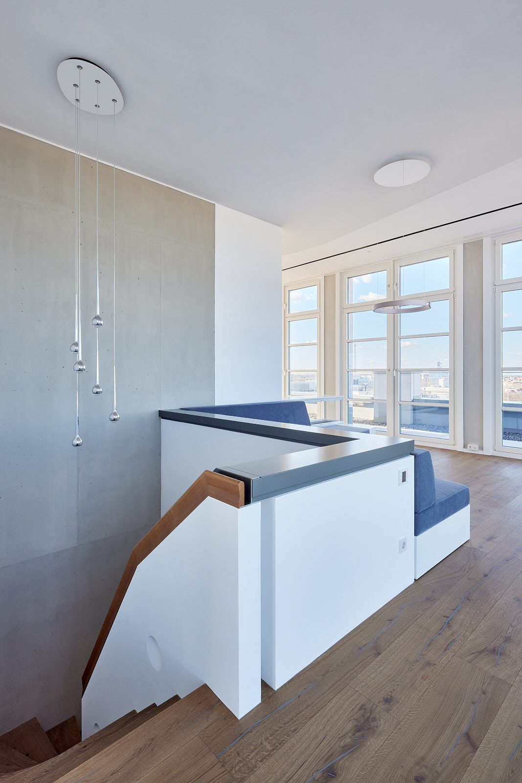 Treppenbereich einer Maisonettewohnung im High West mit weißen Einbauten, Holzhandlauf und großzügiger Verglasung.