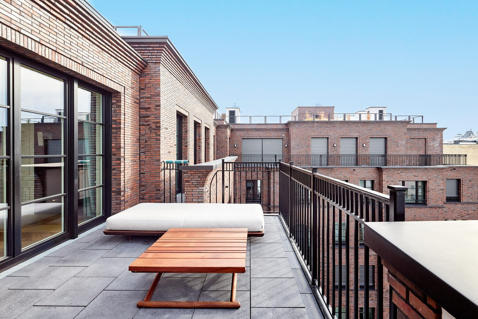 Dachterrasse des Penthouses ALEXANDER-BERLIN in Berlin-Wilmersdorf mit Backsteinarchitektur und Blick über die umliegenden Dächer.