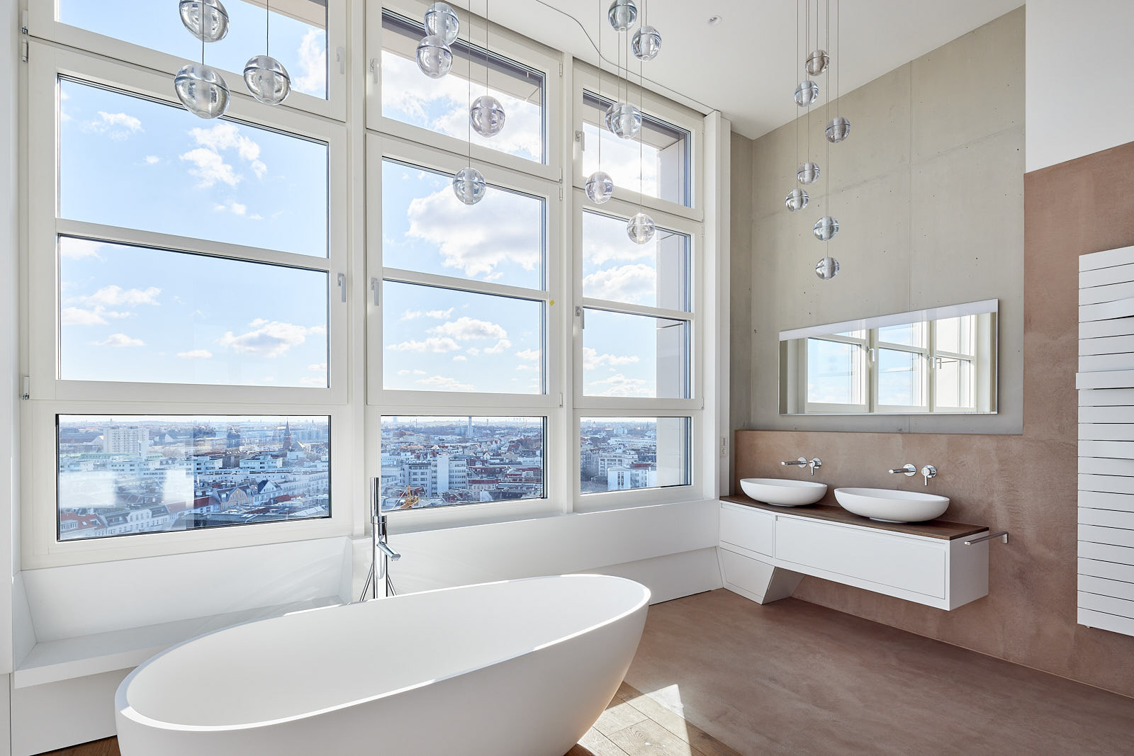 Badezimmer im High West mit freistehender Badewanne, Natursteinflächen und Panoramafenstern über Berlin.