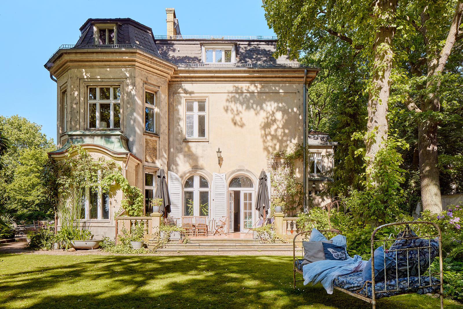 Historischer Schwanenhof auf Berlin-Schwanenwerder mit Mansarddach, polygonalem Erker und Gartenterrasse.