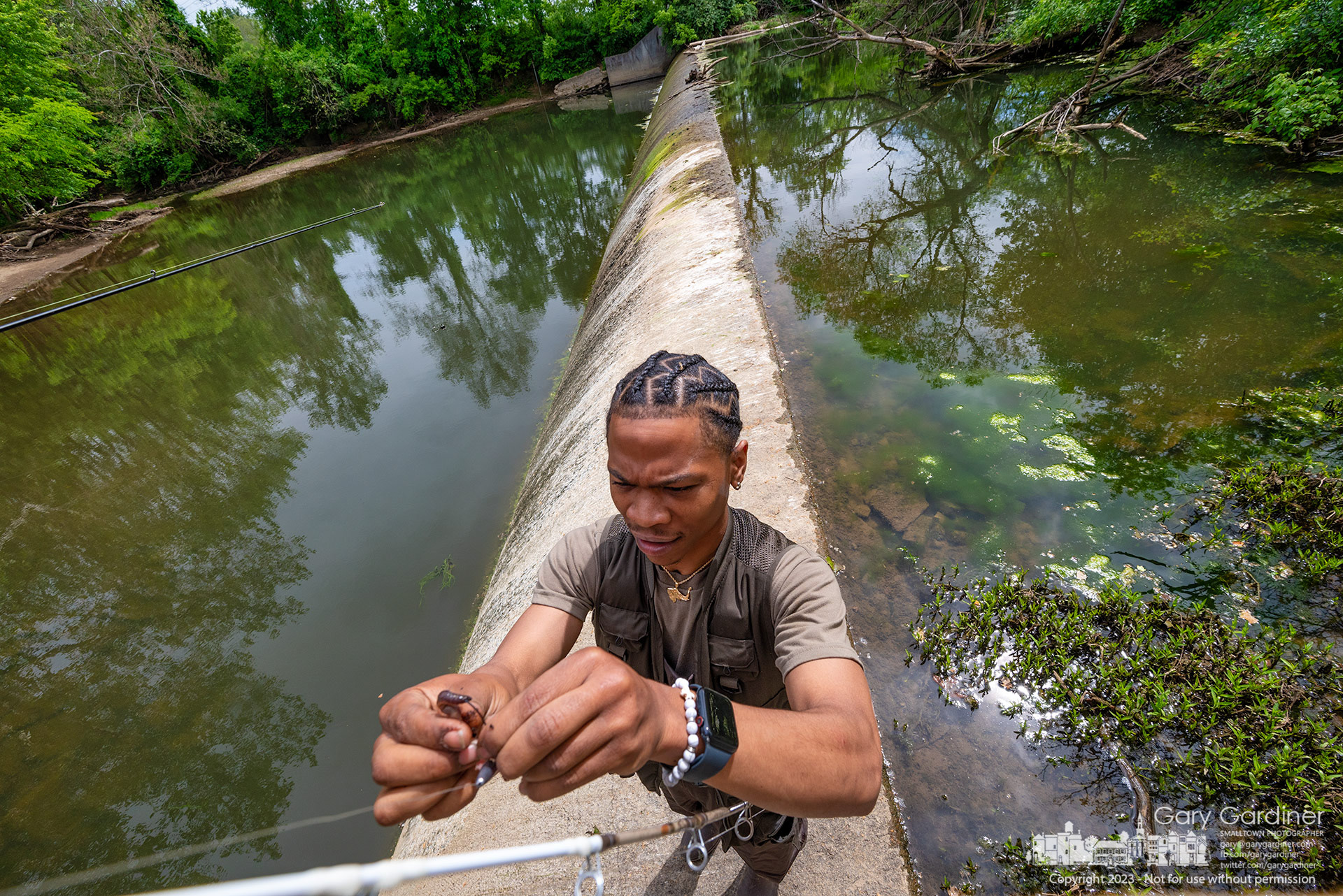 A fisherman at Alum Creek Park North re-baits his hook with a worm, having lost his last one. The creek's flow is so low that parts of the dam, usually submerged, are now exposed. My Final Photo for May 28, 2023.