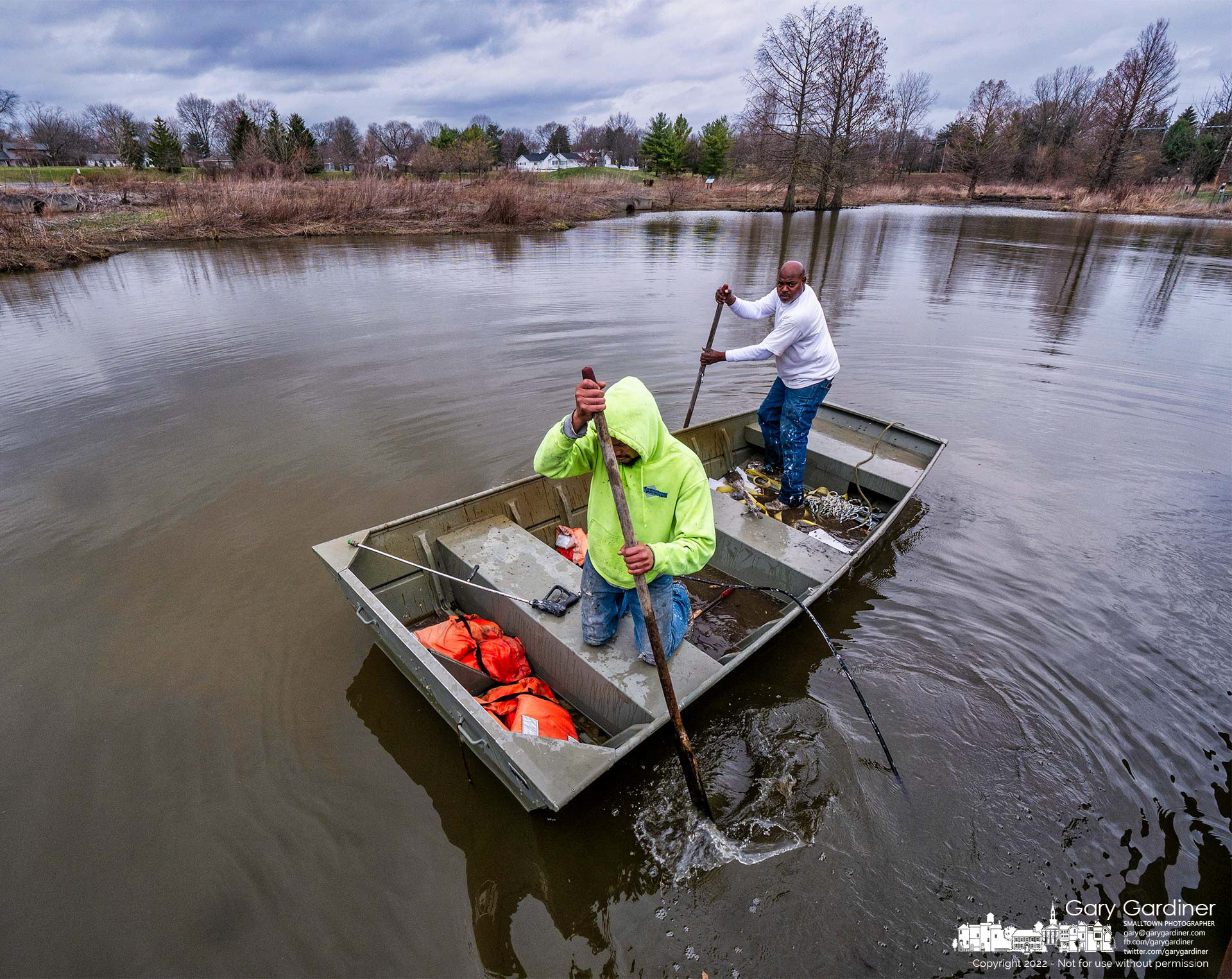 A cleaning crew navigates through the shallow waters of the wetlands at Highlands Aquatic Center after pressure washing the support structure for the walkway along the edge of the waterway. My Final Photo for March 23, 2022.