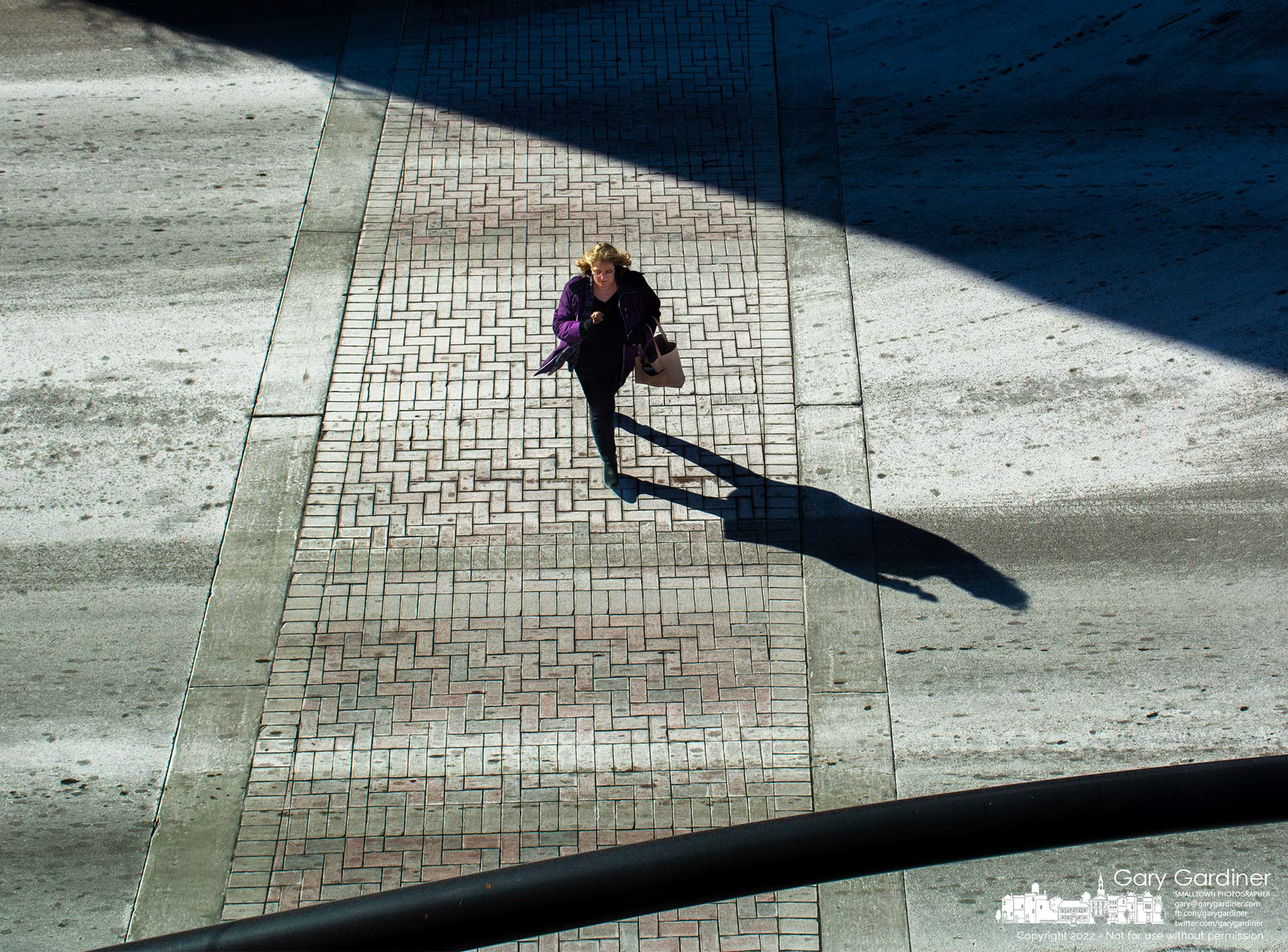 A woman crosses State Street where the red-brick walkway wears a dusty coating of brine sprayed by the city to help melt any snow and ice that maybe happen at the intersection with Main Street. My Final Photo for Jan. 21, 2022.