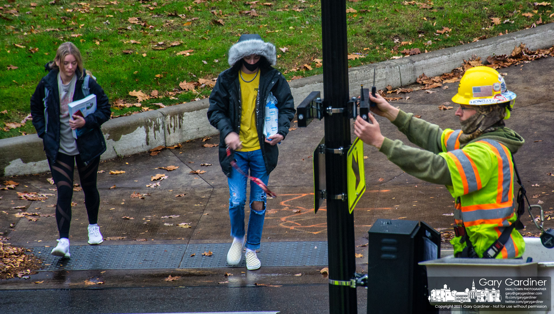 Two Otterbein students step into Main Street where an electrical work crew installs a new set of pedestrian crossing lights and signals for the frequently mid-block crossing on West Main. My Final Photo for Dec. 1, 2021.