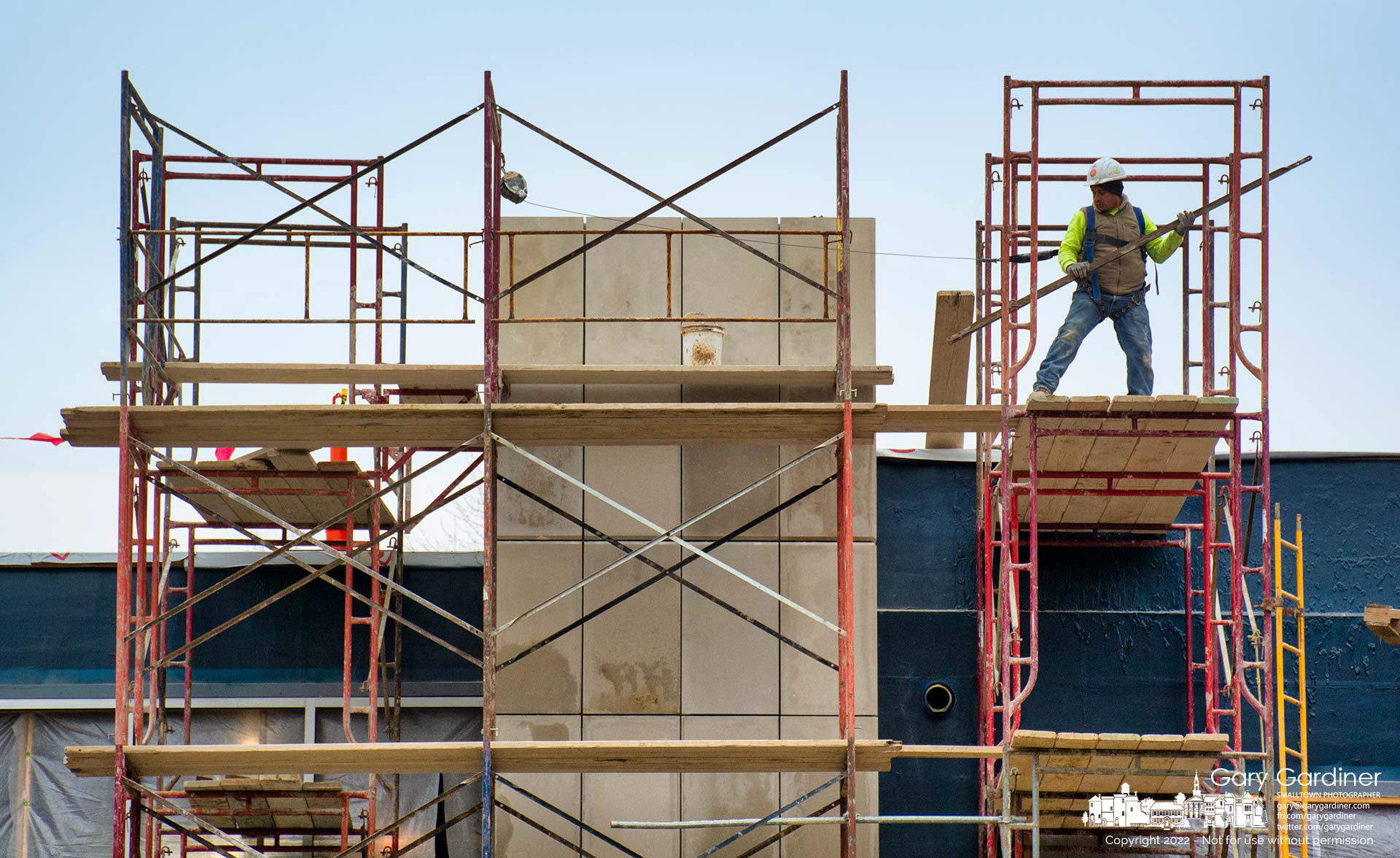 A worker dismantles scaffolding around a just completed pillar at one side of the entrance to the new police station being built on Huber Village Boulevard. My Final Photo for Jan. 14, 2022. 