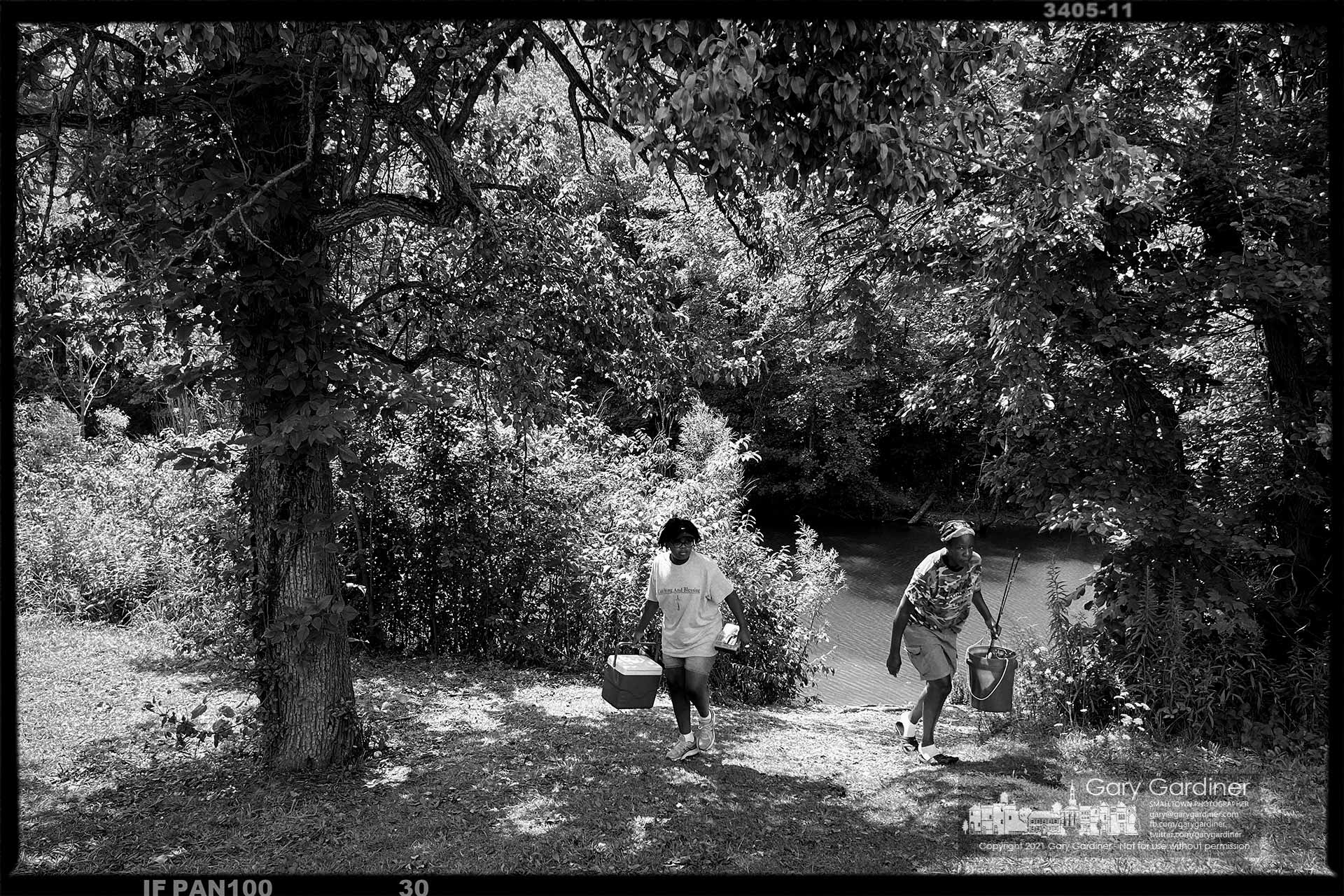 Two women carry their fishing gear to their car as they leave an open area along the shoreline of Hoover Reservoir. My Final Photo for July 30, 2021.