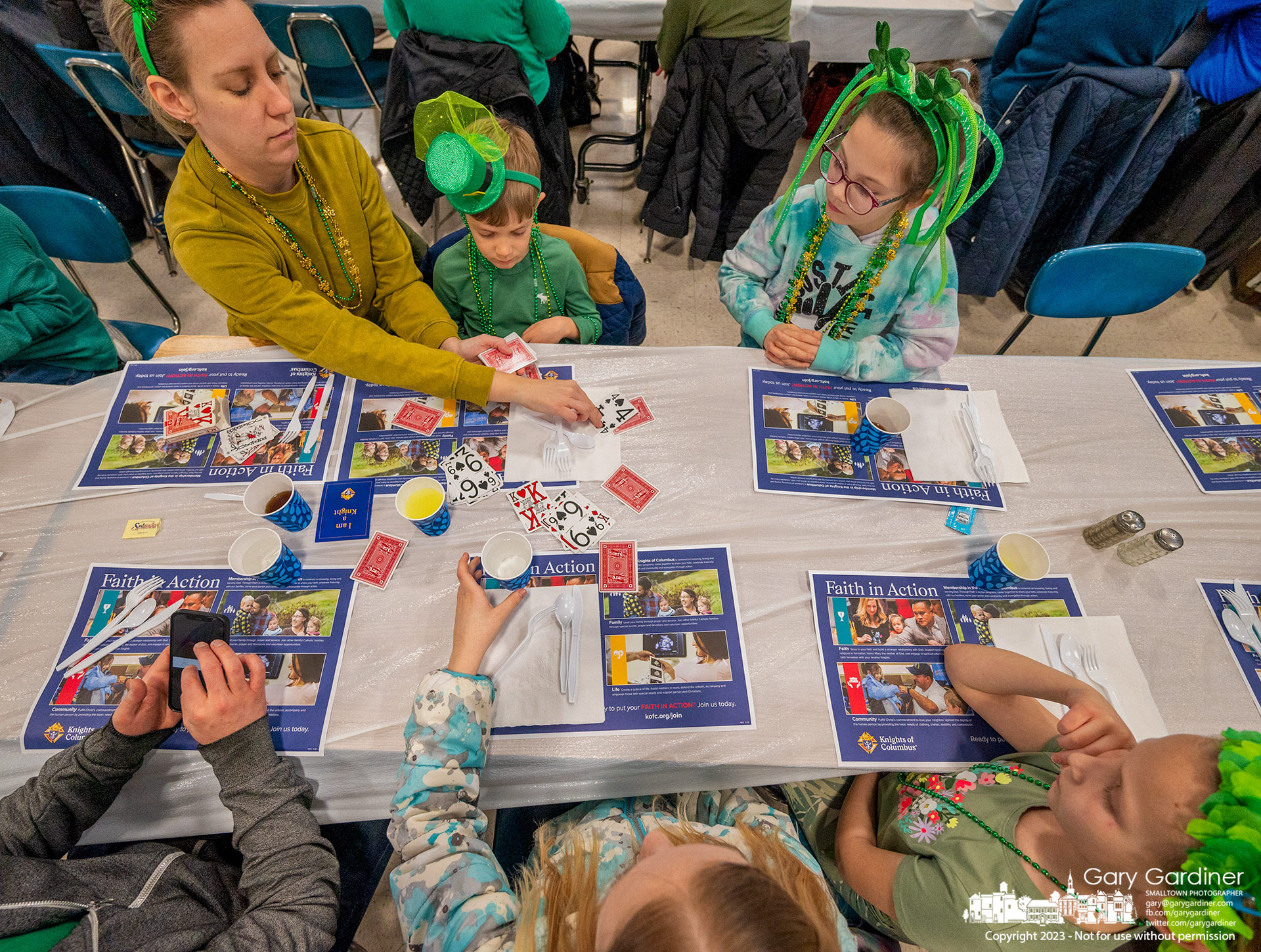 A family wearing St. Patrick green plays a card game after ordering their fish meal at the St. Paul the Apostle Catholic Church's Lenten Friday fish fry. My Final Photo for March 17, 2023. - https://bit.ly/42jjZy2
