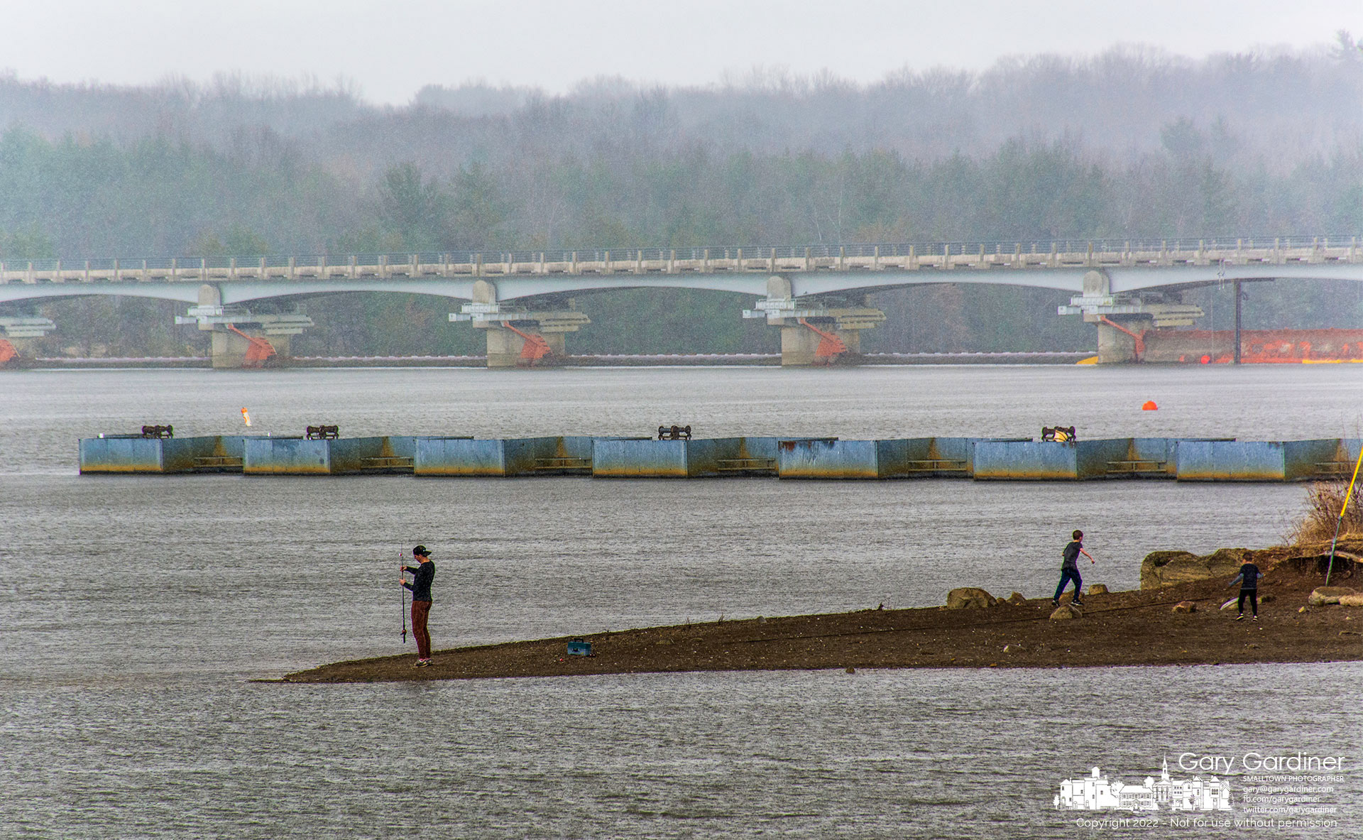 Two children run for the dry safety of a nearby car as their father stores their fishing gear before joining them as a rainstorm approaches at Hoover Reservoir near the dam. My Final Photo for March 6, 2022.