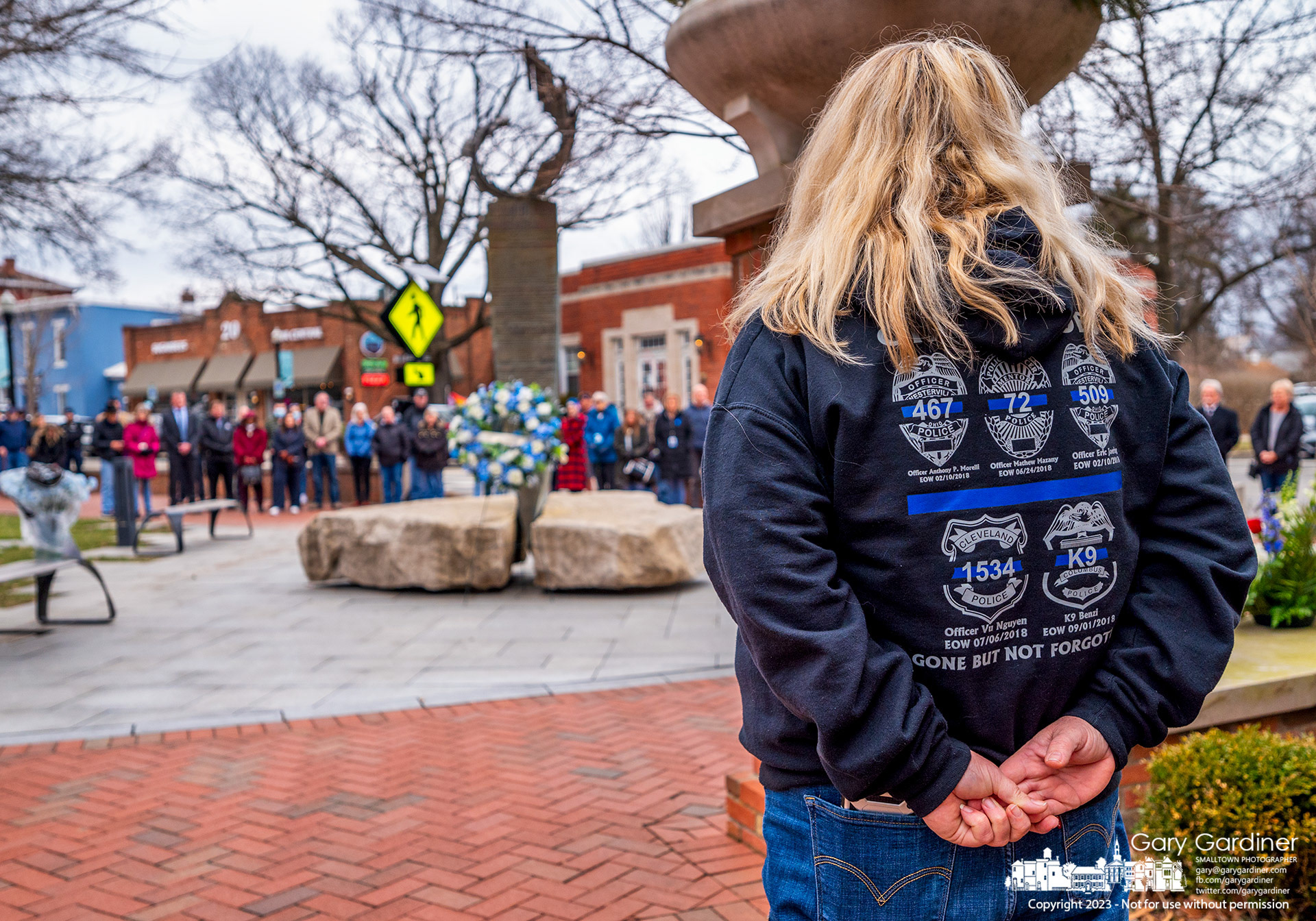 A woman wears a jacket bearing patches marking the names of police officers killed in the line of duty including Westerville officers Morelli and Joering at a wreath-laying ceremony at city hall on the fifth anniversary of their deaths. My Final Photo for February 10, 2023. 