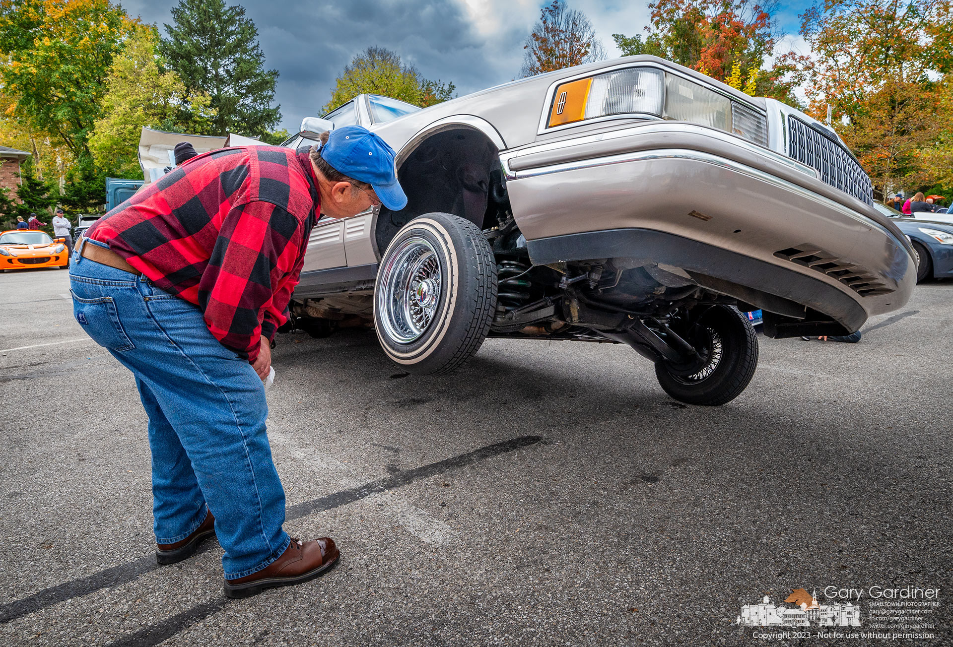 A man studies the undercarriage of an airlifted lowrider at the Columbus Cars and Coffee car show at the parking lot at city hall in Westerville. My Final Photo for October 7, 2023. https://bit.ly/3ZLIHpP