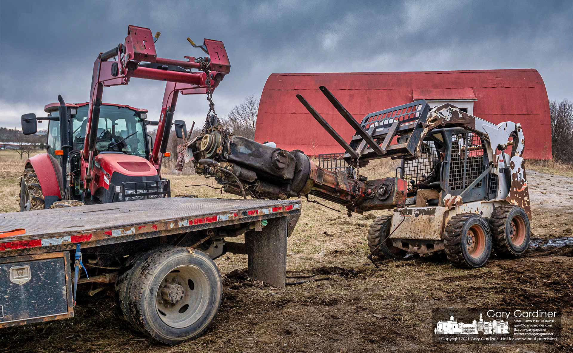 Using a tractor and a Bobcat, the Oliver engine from a Minneapolis-Moline A4T-1600 1970s-era tractor from the Braun Farm is lifted on a truck bed for transport to a scrap yard. My Final Photo for March 15, 2021.