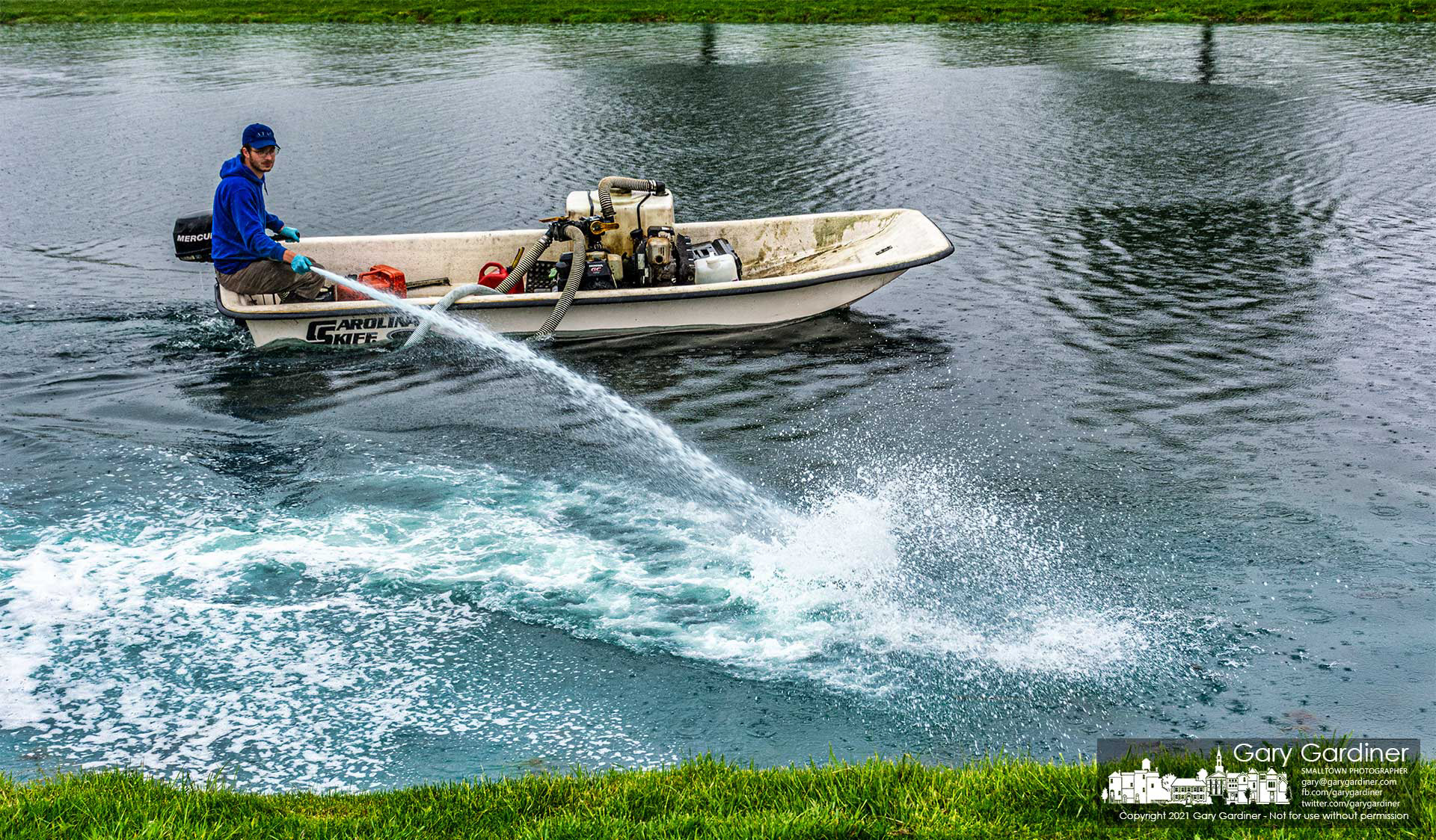 A contractor sprays copper sulfate into the pond in front of the community center to prevent the growth of algae this summer. My Final Photo for April 29, 2021.