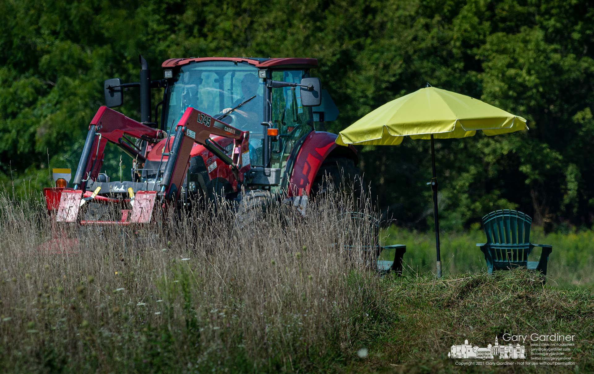 Kevin Scott steers his tractor around an umbrella and lawn chairs placed in an open space in the farm field he cutting for hay on North West Street. My Final Photo for Sept. 3, 2021.