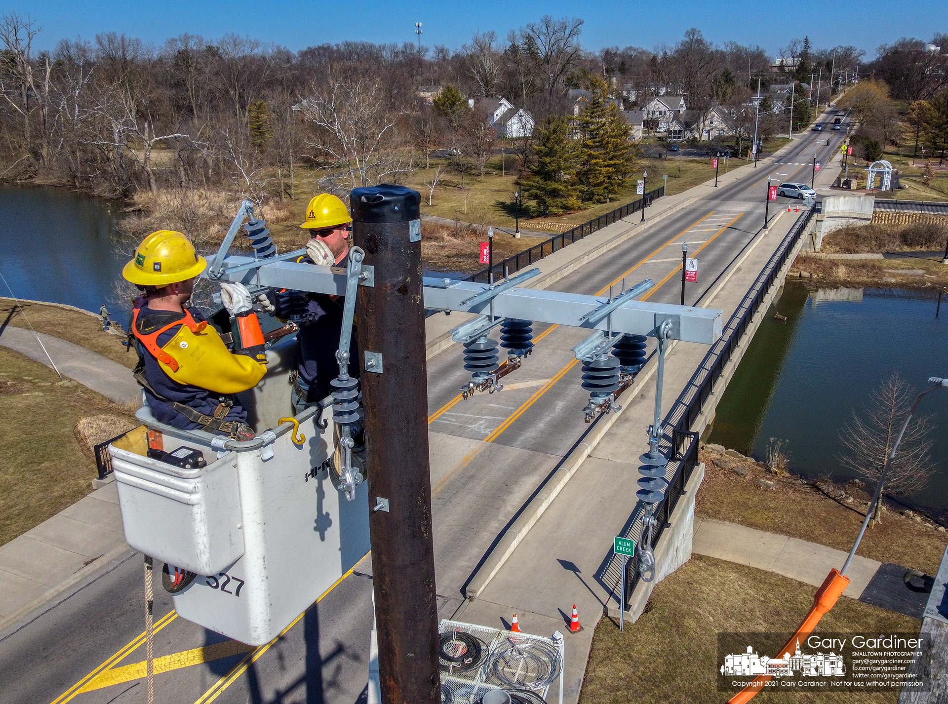 A city electric crew installs a crossbar on a new utility pole at the Main Street bridge where power lines will be directed underground as the nearby substation is upgraded. My Final Photo for March 3, 2021.