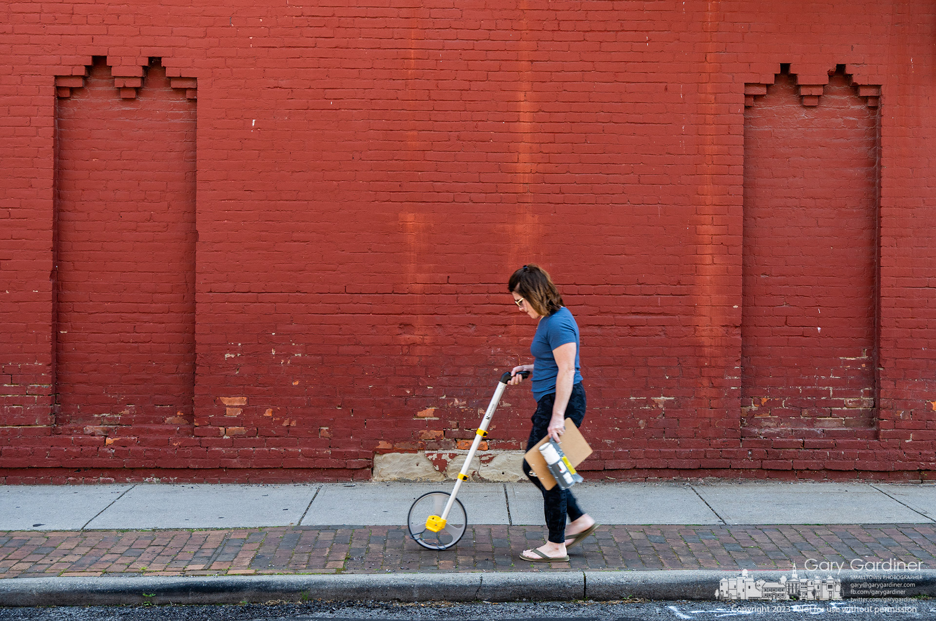 Lynn Aventino, Executive Director of Uptown Westerville Inc., measures spaces for vendor booths on East College for the first Fourth Friday street festival. My Final Photo for May 25, 2023. 