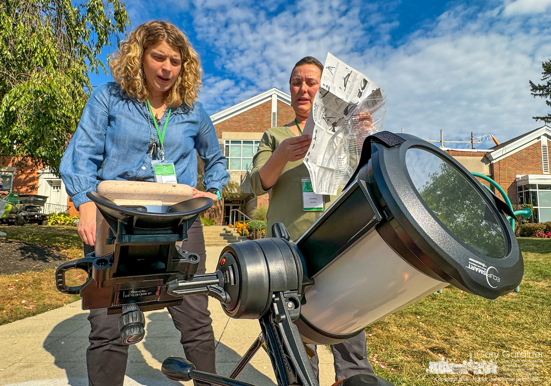 Librarians read the instructions for setting up the Westerville Library's new telescope with an eclipse filter as it prepares for Saturday's partial annular eclipse. My Final Photo for October 12, 2023. https://bit.ly/46s6Qo5