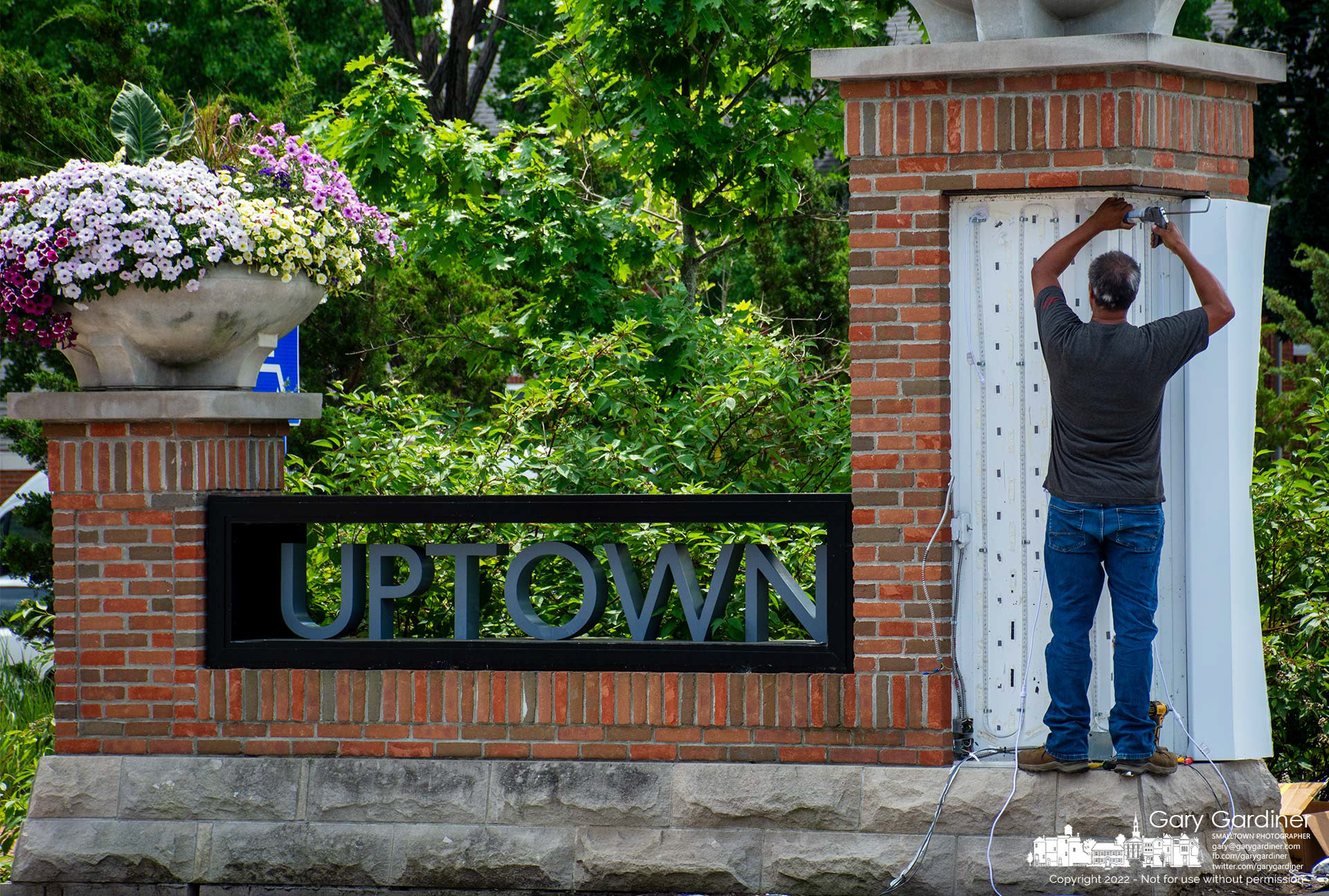 An electrician upgrades the LED lights in the pillars at the entrance to the parking lot at city hall to a more powerful set of lights that also offer a wide spectrum of color choices. My Final Photo for July 1, 2022.