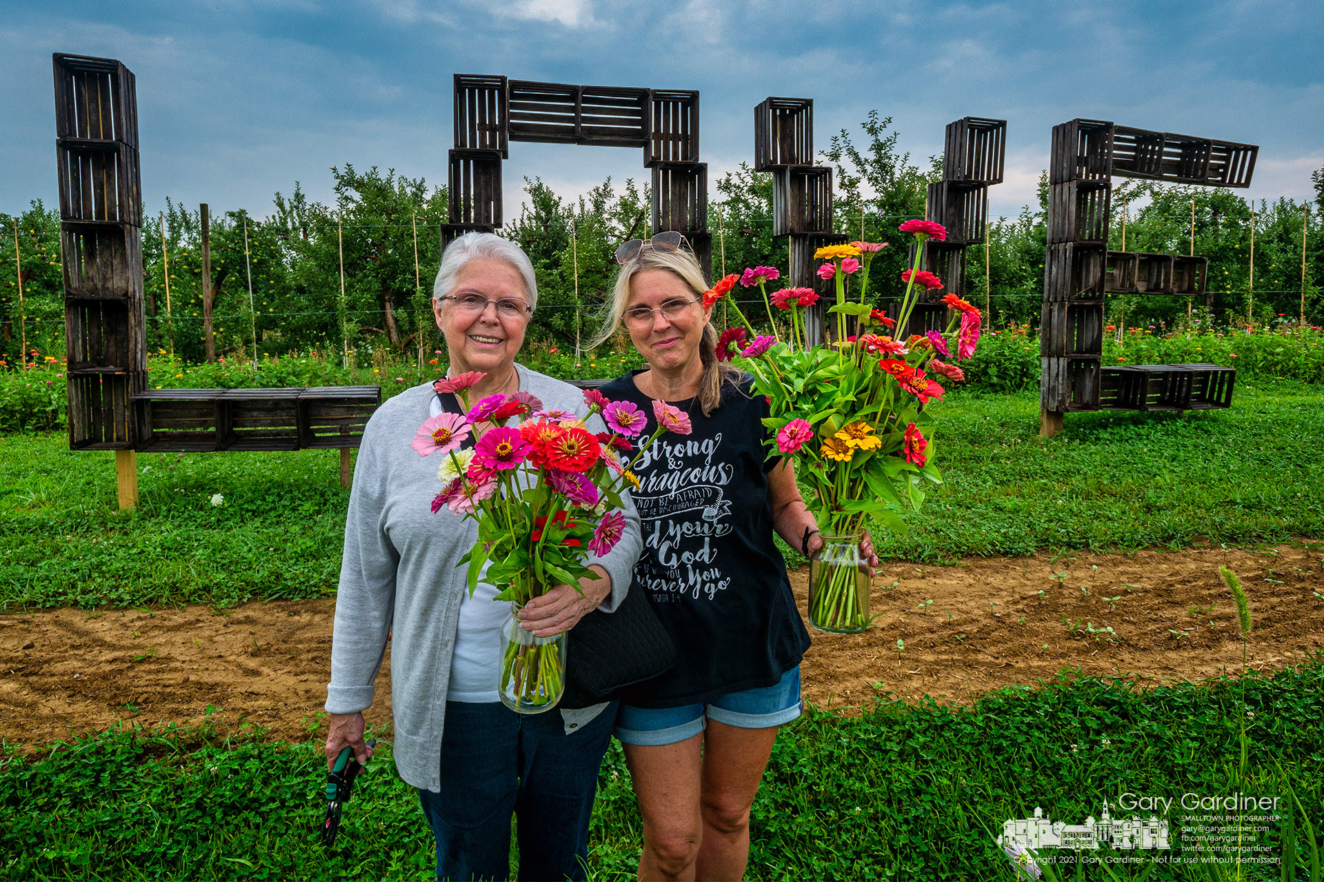 A mother and daughter pose in front of a "Love" sign sculpted from fruit boxes after having picked flowers at Branstool's Orchard in Utica. My Final Photo for July 29, 2021.