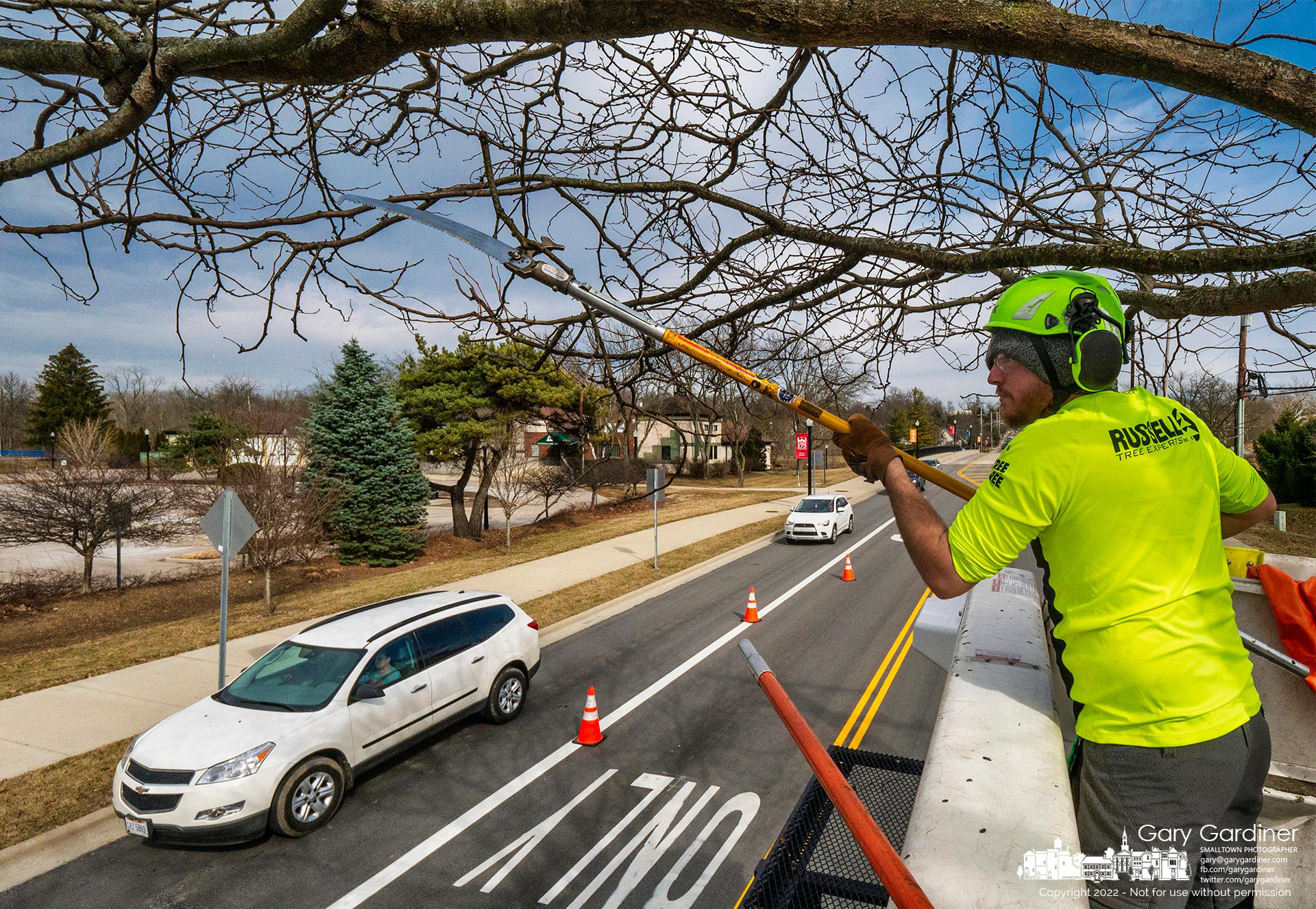 A tree trimmer reaches stretches cut away a dead, damaged, or disruptive branch from a tree near the bridge over Alum Creek on West Main Street. My Final Photo for March 1, 2022.
