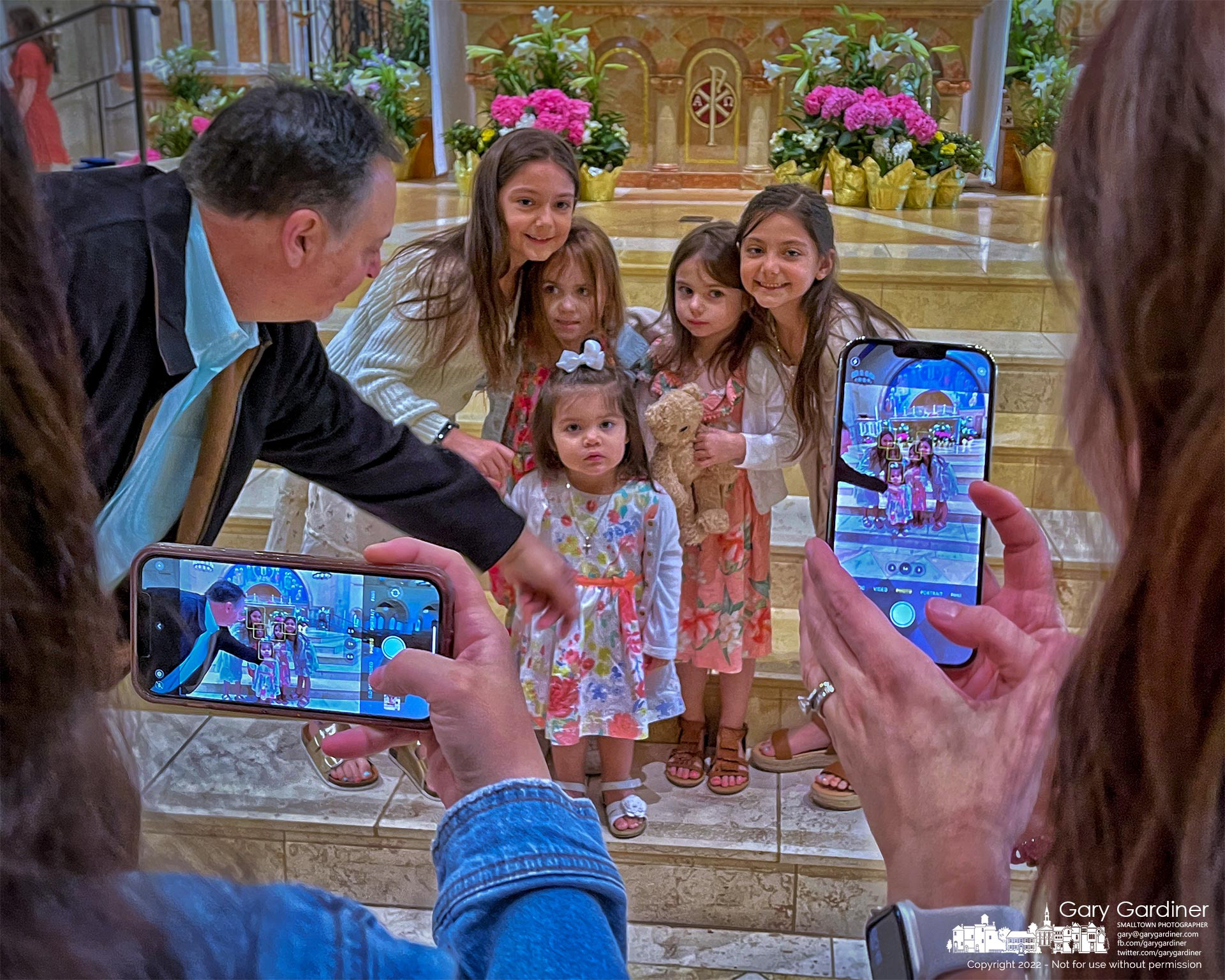A man leans in to help with staging and posing as five youngsters pose for photos in front of the altar at St. Paul the Apostle Catholic Church after Easter Sunday Mass. My Final Photo for April 17, 2022.