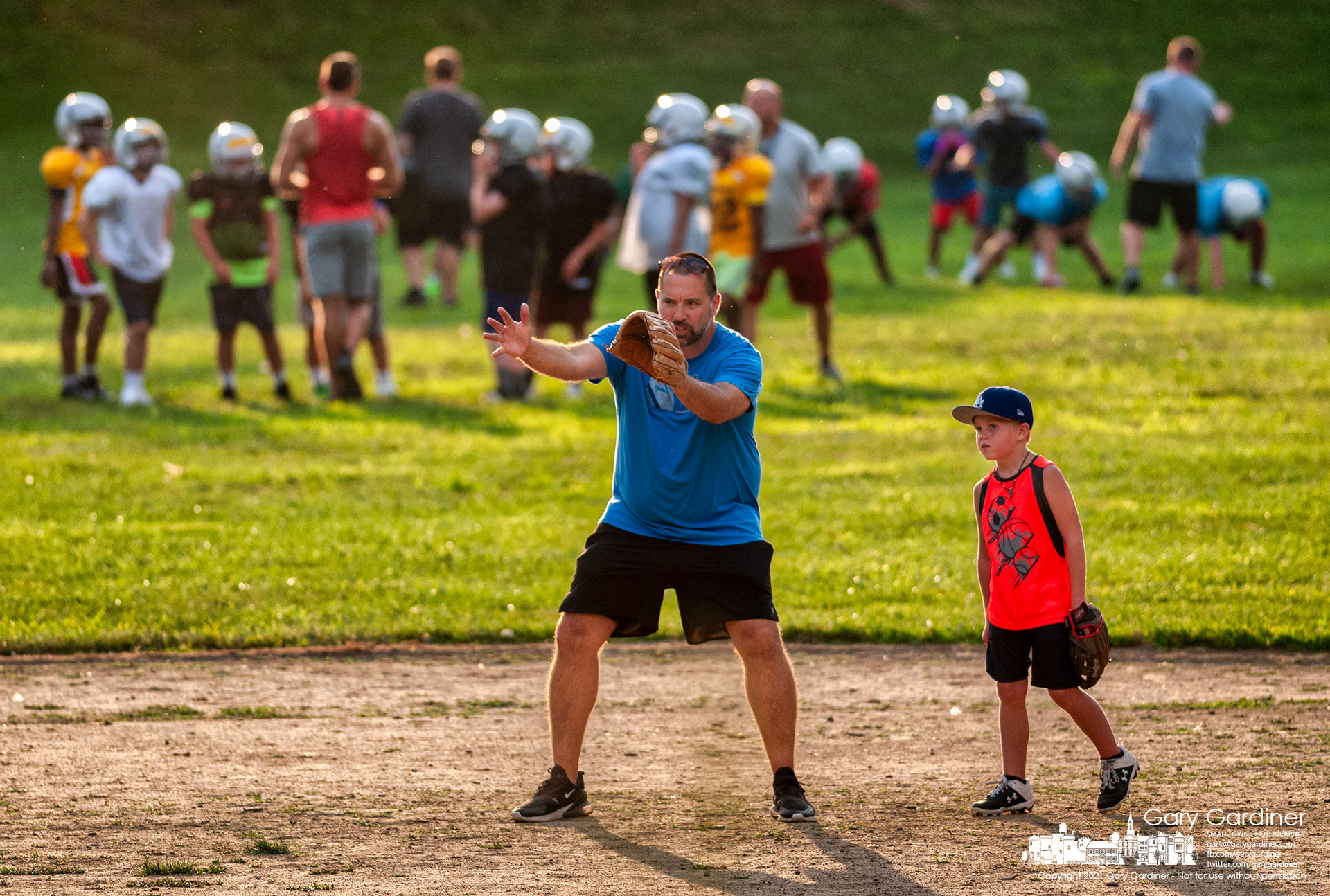 A baseball coach instructs one of his players at Alum Creek Park where other coaches work with the football team practicing at the other end of the field. My Final Photo for Aug. 5, 2021.