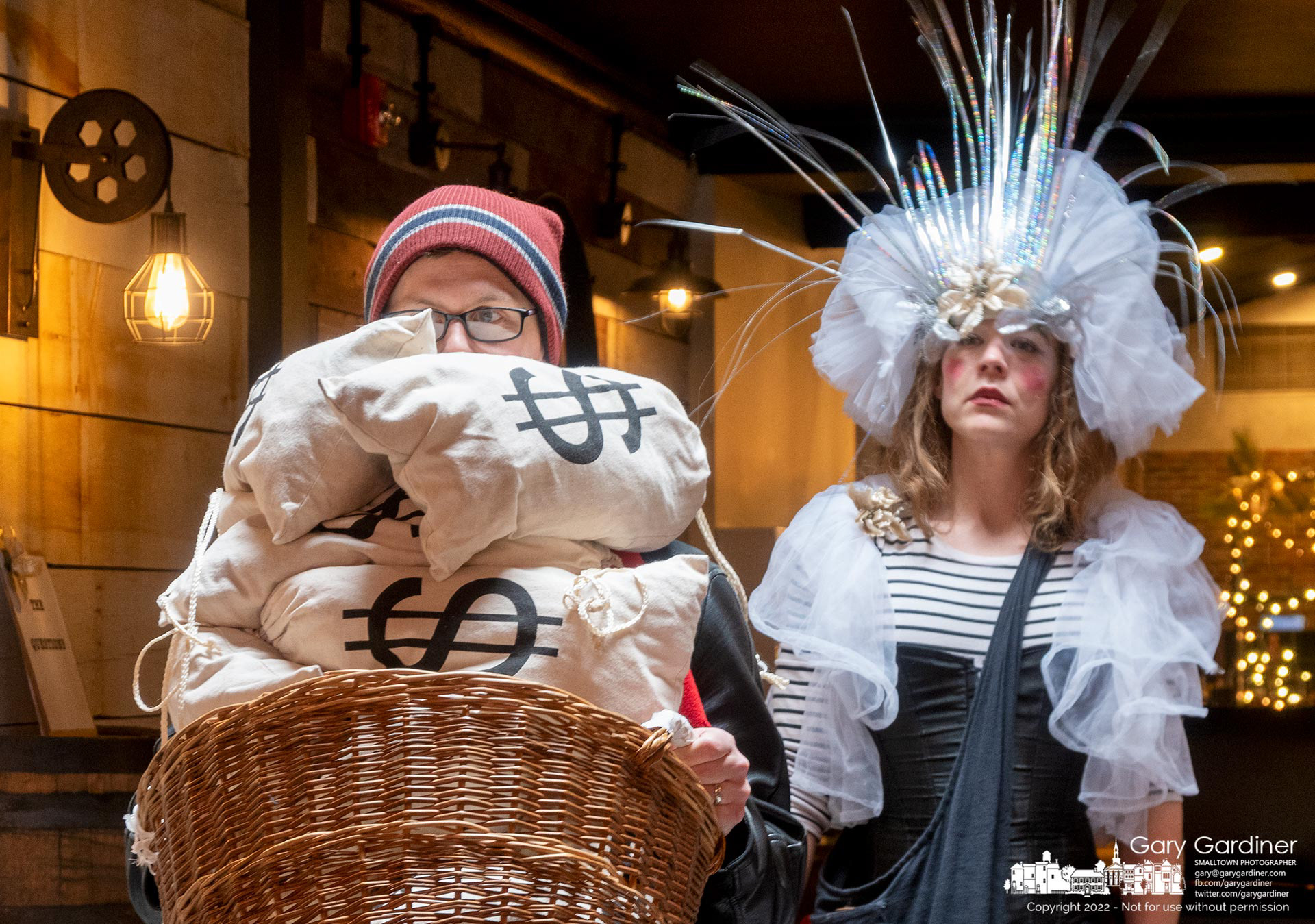 Scrooge, portrayed by an audience member, struggles with a basket of money as he is led through a Saturday afternoon presentation of Uptown Scrooge by Good Medicine Productions. My Final Photo for December 17, 2022.