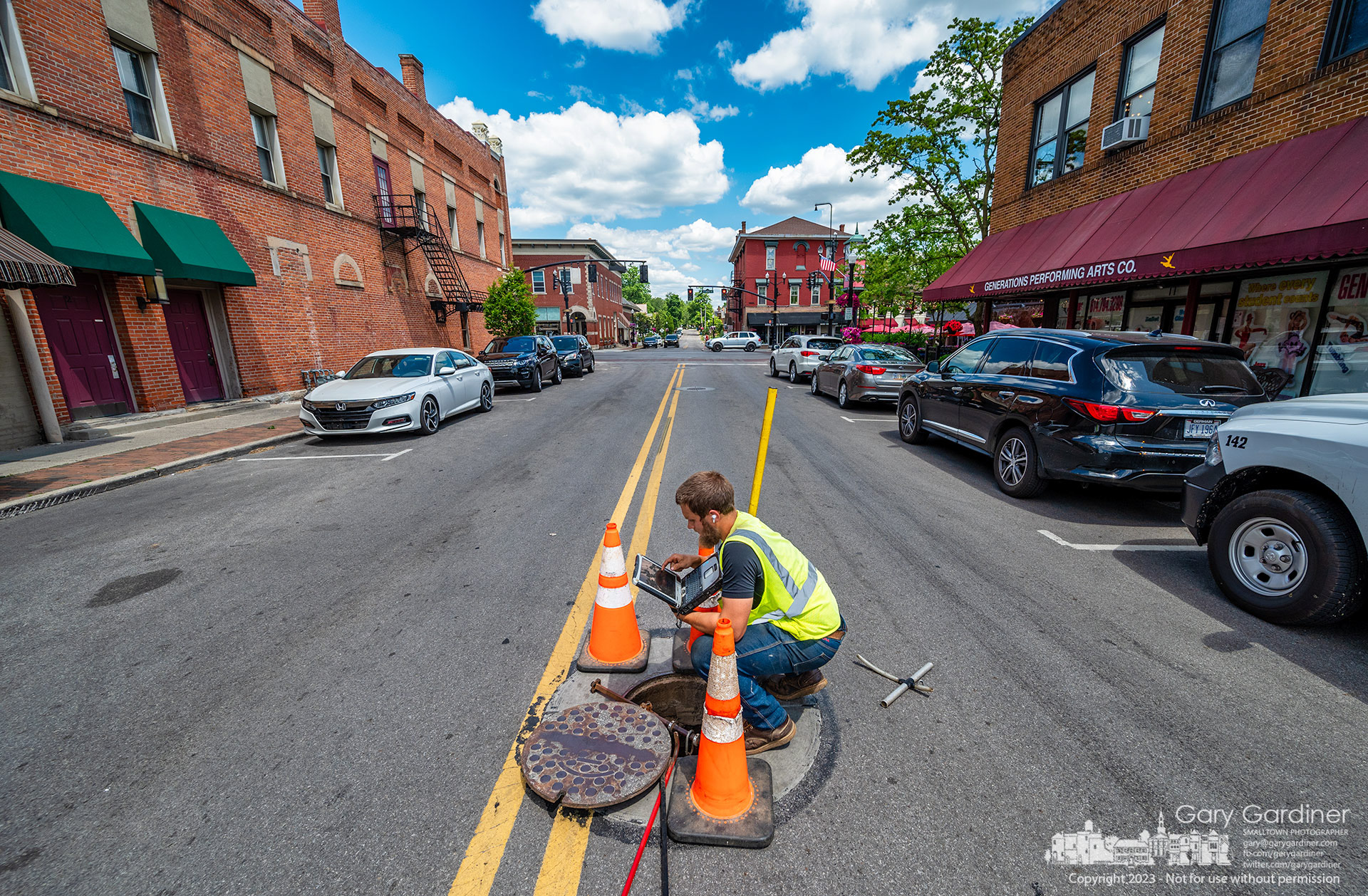 An inspector is testing the wireless connection to an autonomous, self-powered video camera, which he has lowered into a sanitary sewer on East College in Uptown. The city is conducting tests on sewers to identify broken or damaged pipes and obstructions, such as roots. My Final Photo for May 30, 2023.
