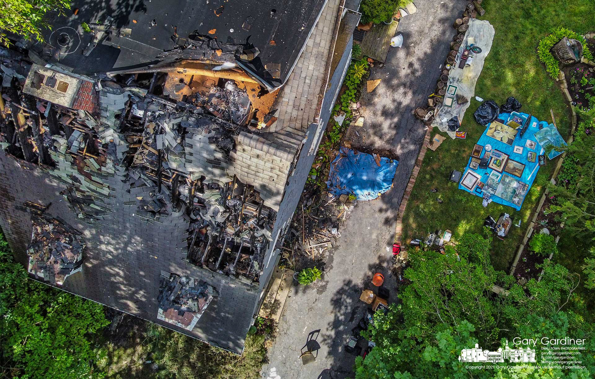 A portion of a family's collection of art and personal belongings are spread out on tarps beside their damaged home after an overnight fire they say started with an overheated lithium-ion battery charger. My Final Photo for July 2, 2021. 
