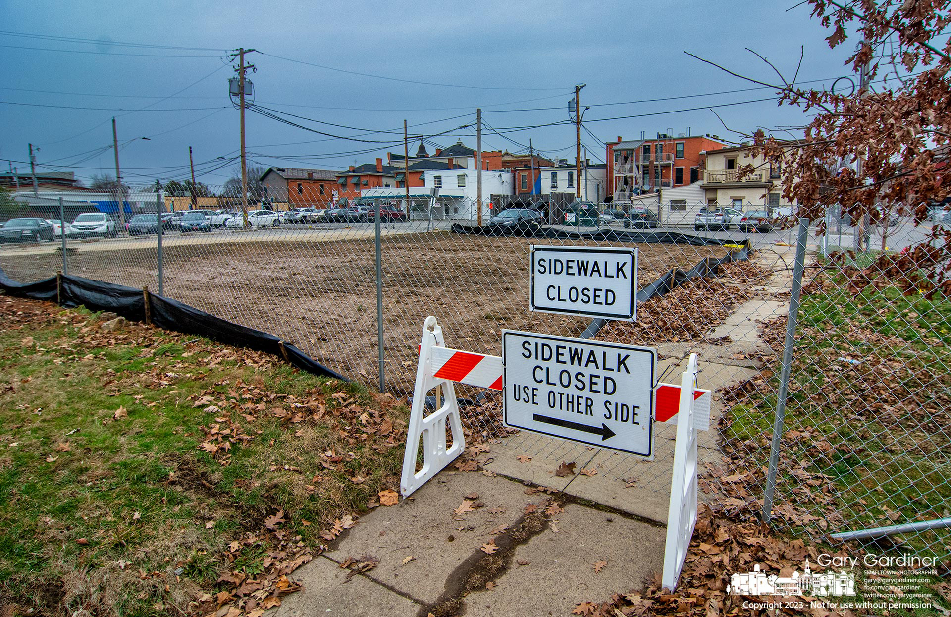 A construction fence now encircles the plot of land on West College where a building with ground-floor businesses under four apartments will be built. My Final Photo for January 10, 2023.