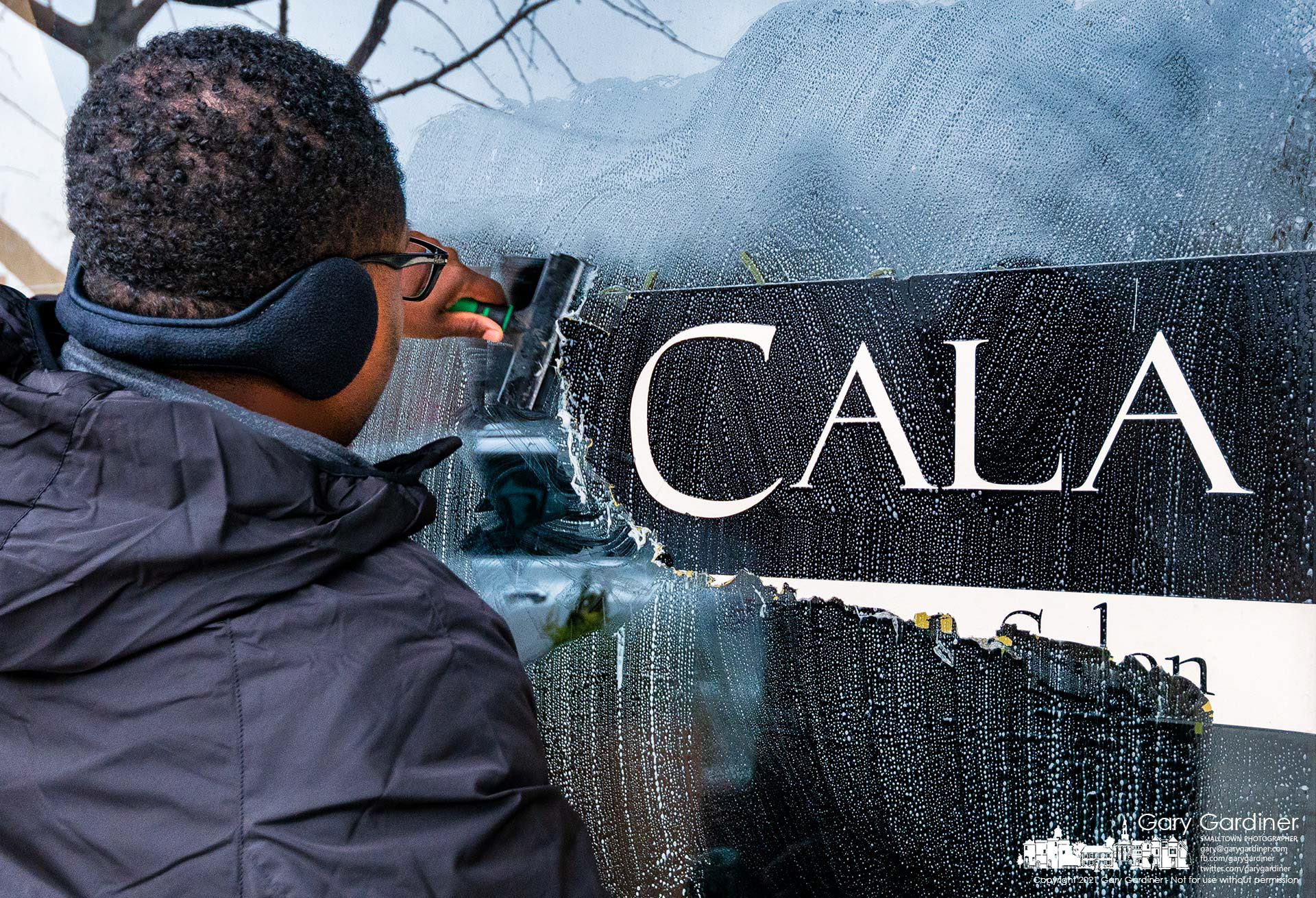 Micah scrapes away the signage for Cala Luna Salon as the building is prepared for the opening of Sugarbees, a chocolate shop, in 2022. My Final Photo for Dec. 29, 2021.