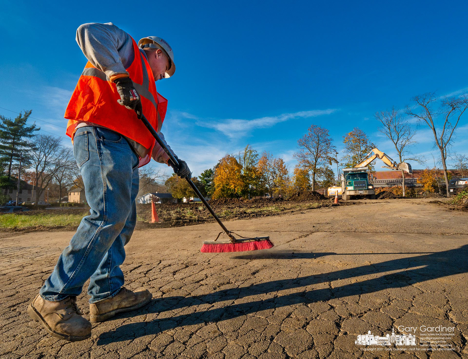 A worker sweeps Oakland Ave. keeping it clear of rocks and debris from trucks and equipment removing the remains of two houses on South State St. demolished to make way for an apartment building and businesses. My Final Photo for Nov. 16, 2021.