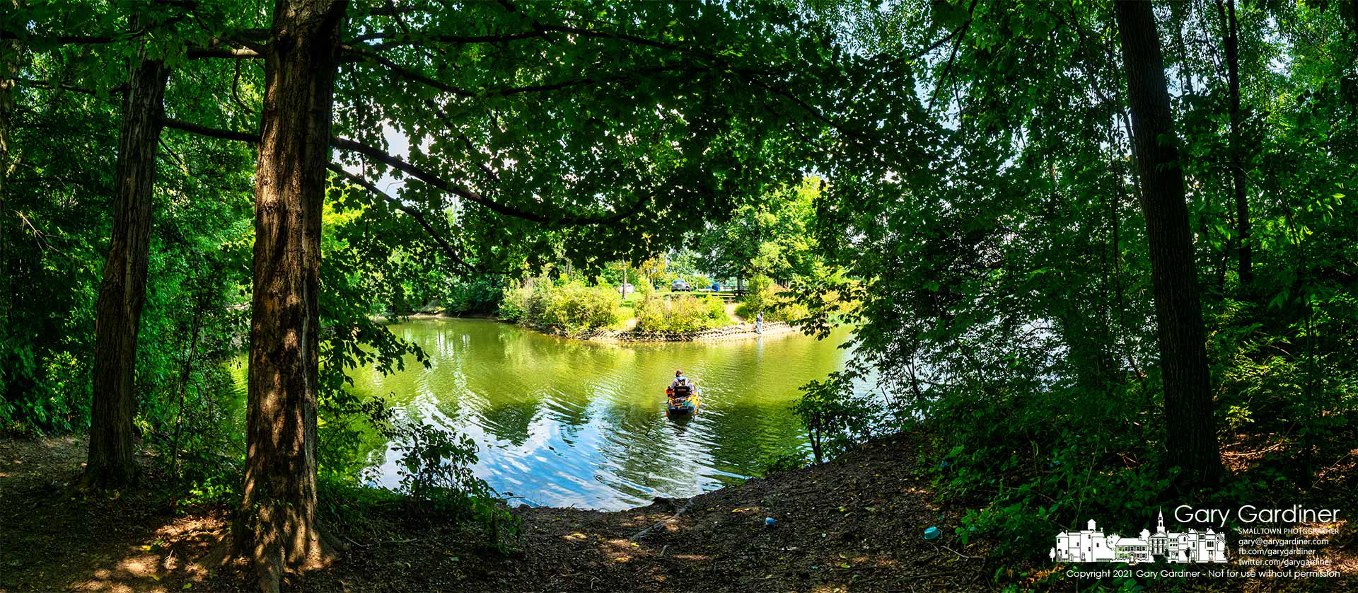 A fisherman steadies his kayak beside the shadows from the tree-lined shoreline in shallow waters on the edge of Hoover Reservoir. My Final Photo for Aug. 20, 2021.