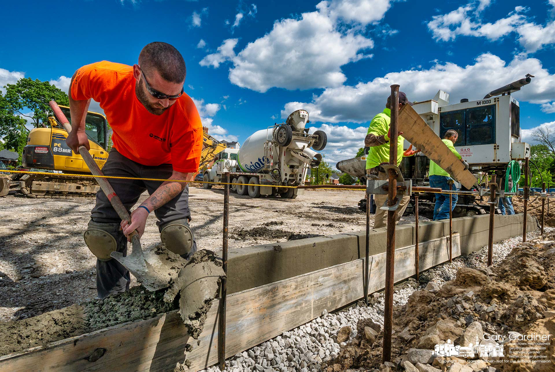 A worker removes machine-poured concrete gutter to level it for handicapped spaces in the new parking lot behind city hall. My Final Photo for May 11, 2021.