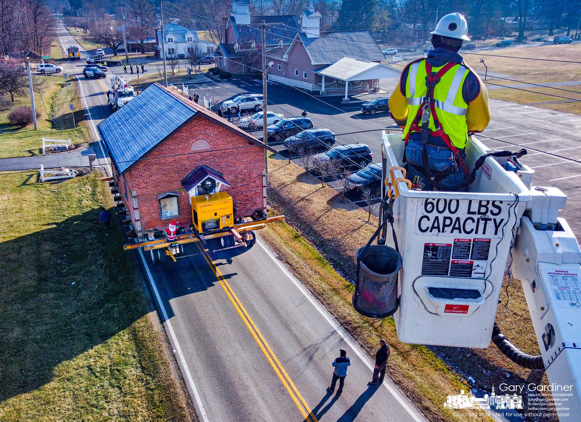 An AEP linesman raises a disconnected power line out of the way as the old Genoa Township Town Hall is moved from its original location at Big Walnut and Tussic to McNamara Park. My Final Photo for December 21, 2022.