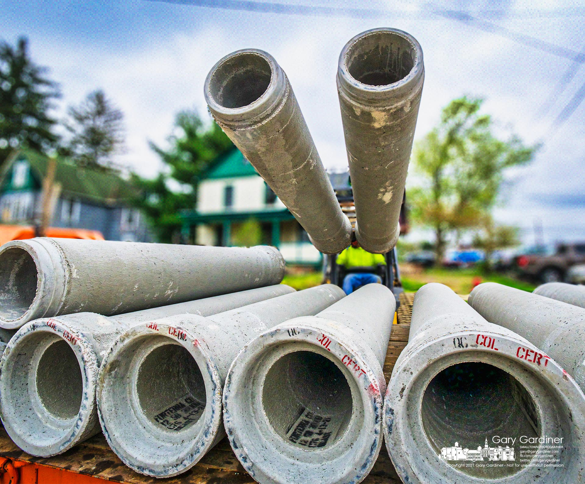 A truckload of concrete drain pipes is offloaded on West College where the first week of construction for the new parking lot behind city hall ended. My Final Photo for April 16, 2021.