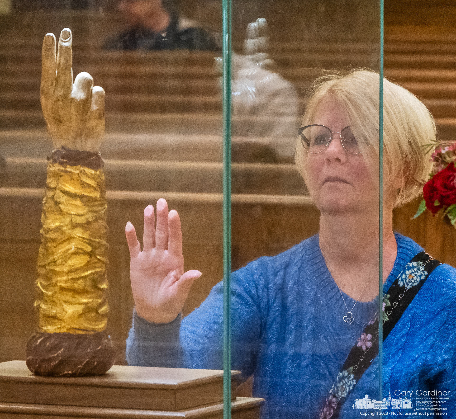 A woman places her hand on the glass case holding the St. Jude Thaddeus relic being shown at St. Paul the Apostle church in Westerville. My Final Photo for October 30, 2023. https://bit.ly/3FHmYq1