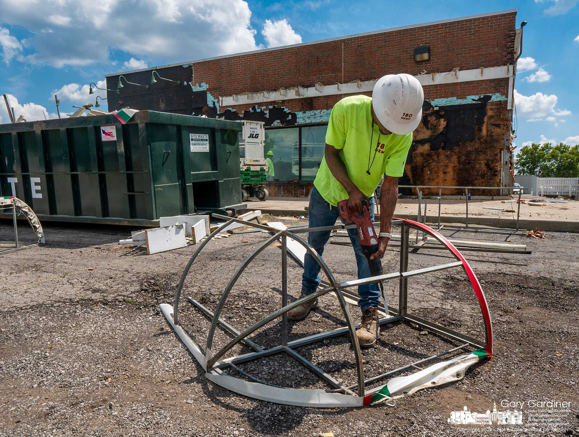 A demolition crew worker uses an electric hacksaw to dismantle the awning framework that covered the front and side windows of Flowerama at State and Schrock as the building is converted to use by FCBank. My Final Photo for August 19, 2022.